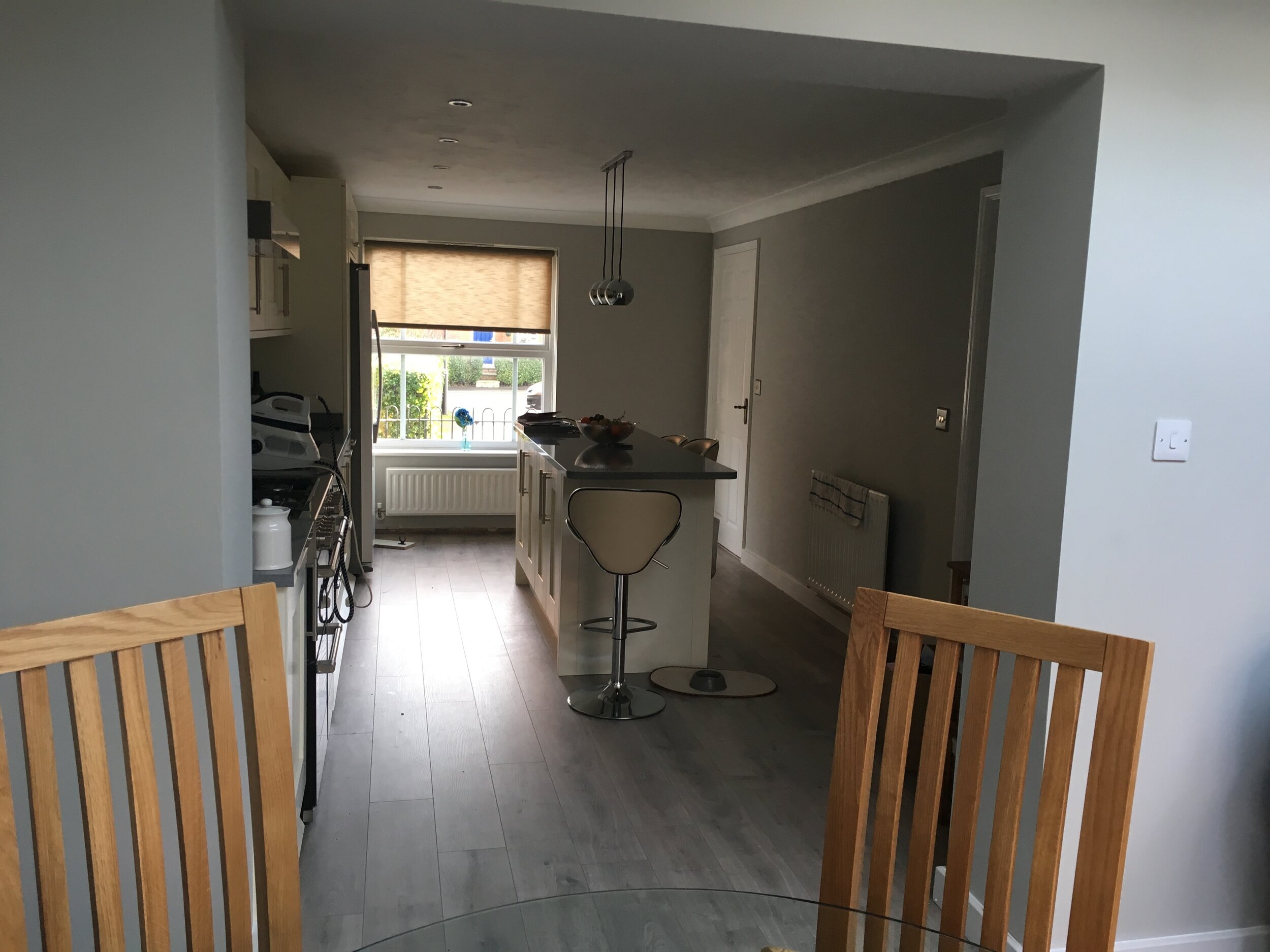 A kitchen with a window, a kitchen island with bar stools, and a dining table with chairs.