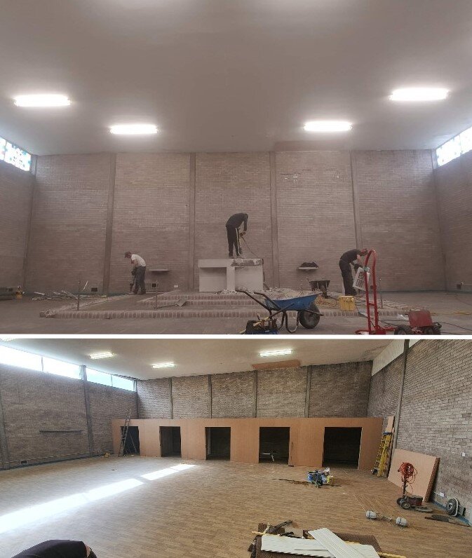 Interior of a building under renovation, featuring workers installing flooring and construction tools.