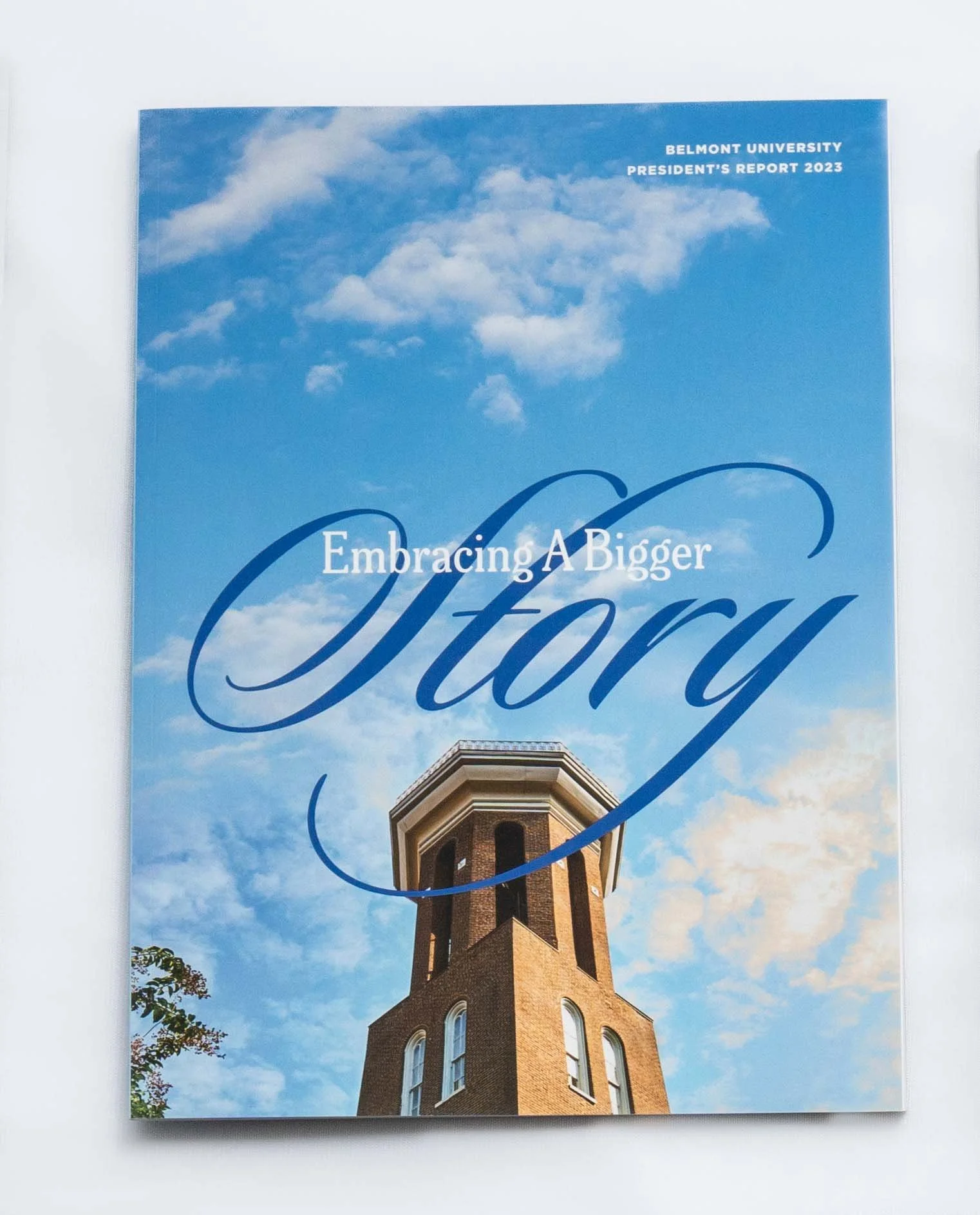 Cover page of Belmont University's 2023 President's Report with a blue sky and clouds, featuring a brick tower with arched windows.