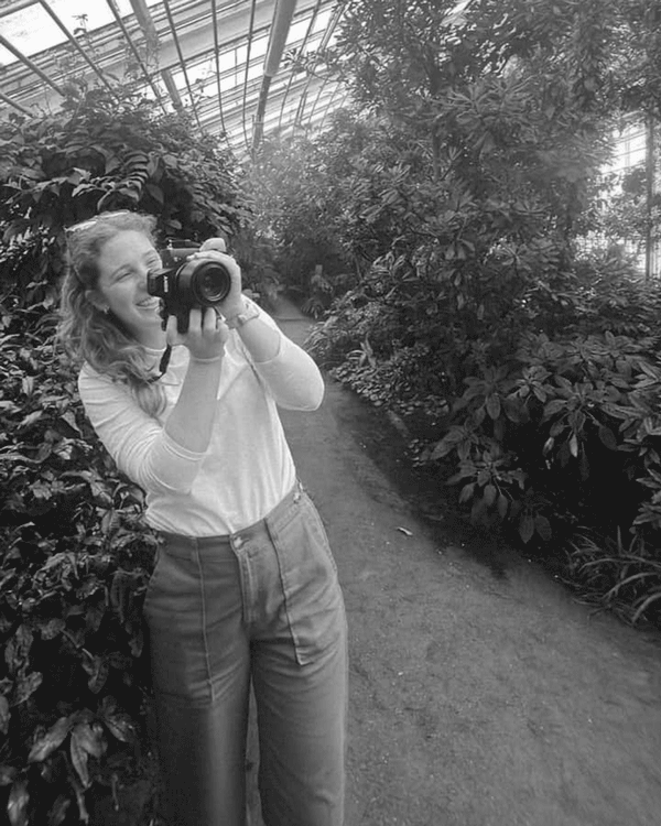 In black and white, a series of images of Mary Puls, Nashville-based storyteller, photographer, and graphic designer, working with a camera.