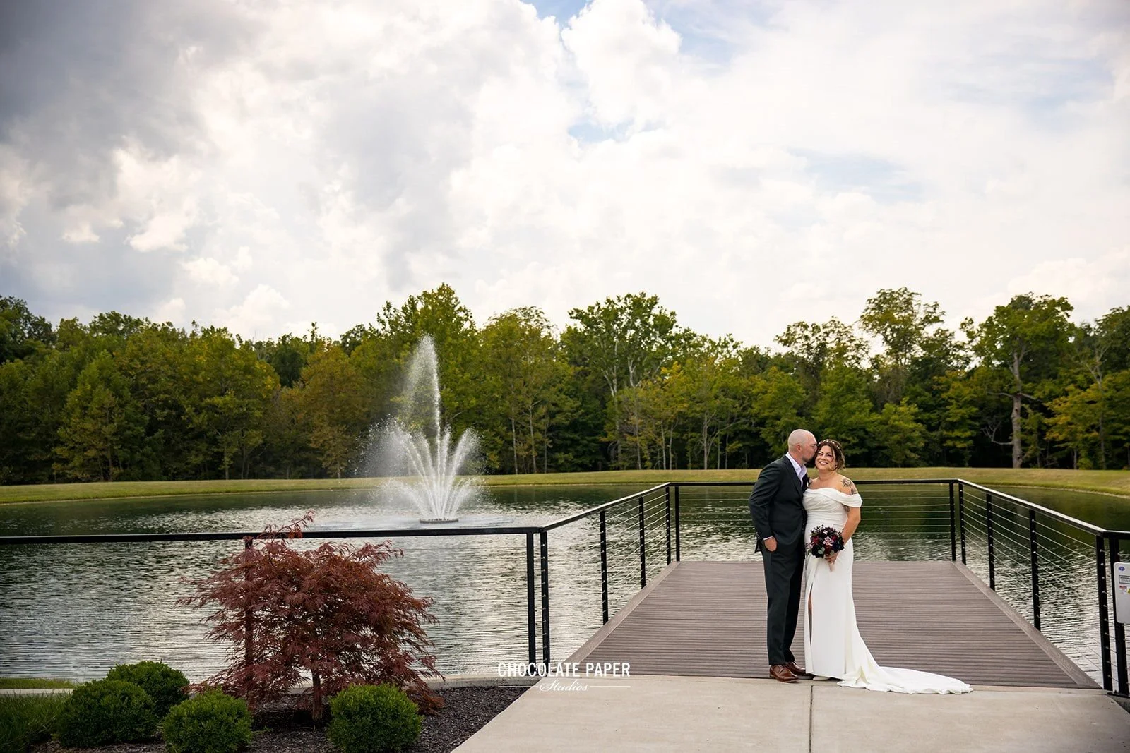Bride & Groom pose for wedding day photos at an outdoor wedding venue with waterfront ceremony & forest views.