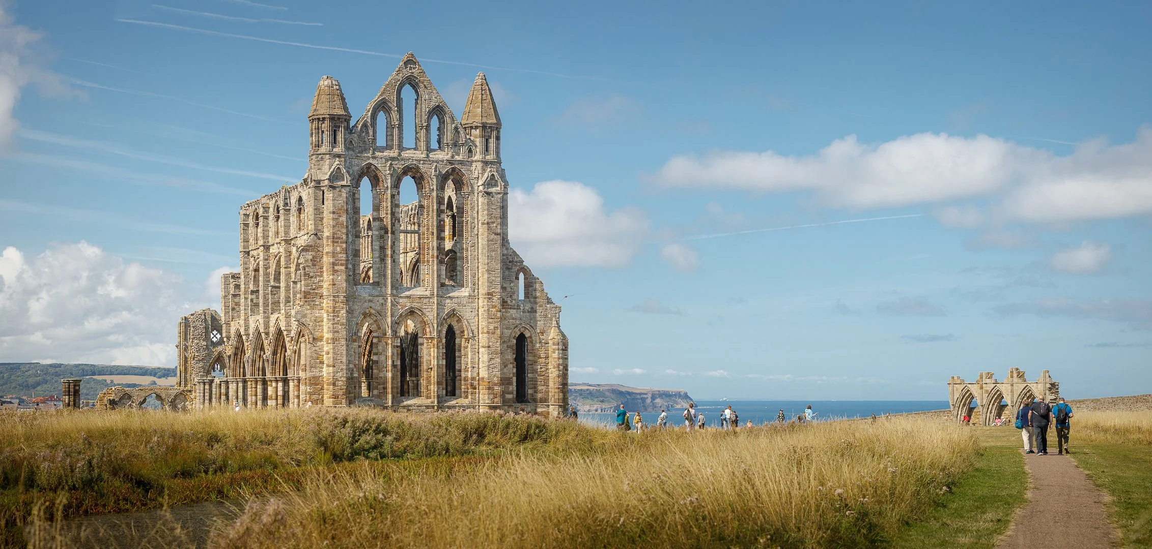Tourists explore the grounds of Whitby Abbey on a bright summers day