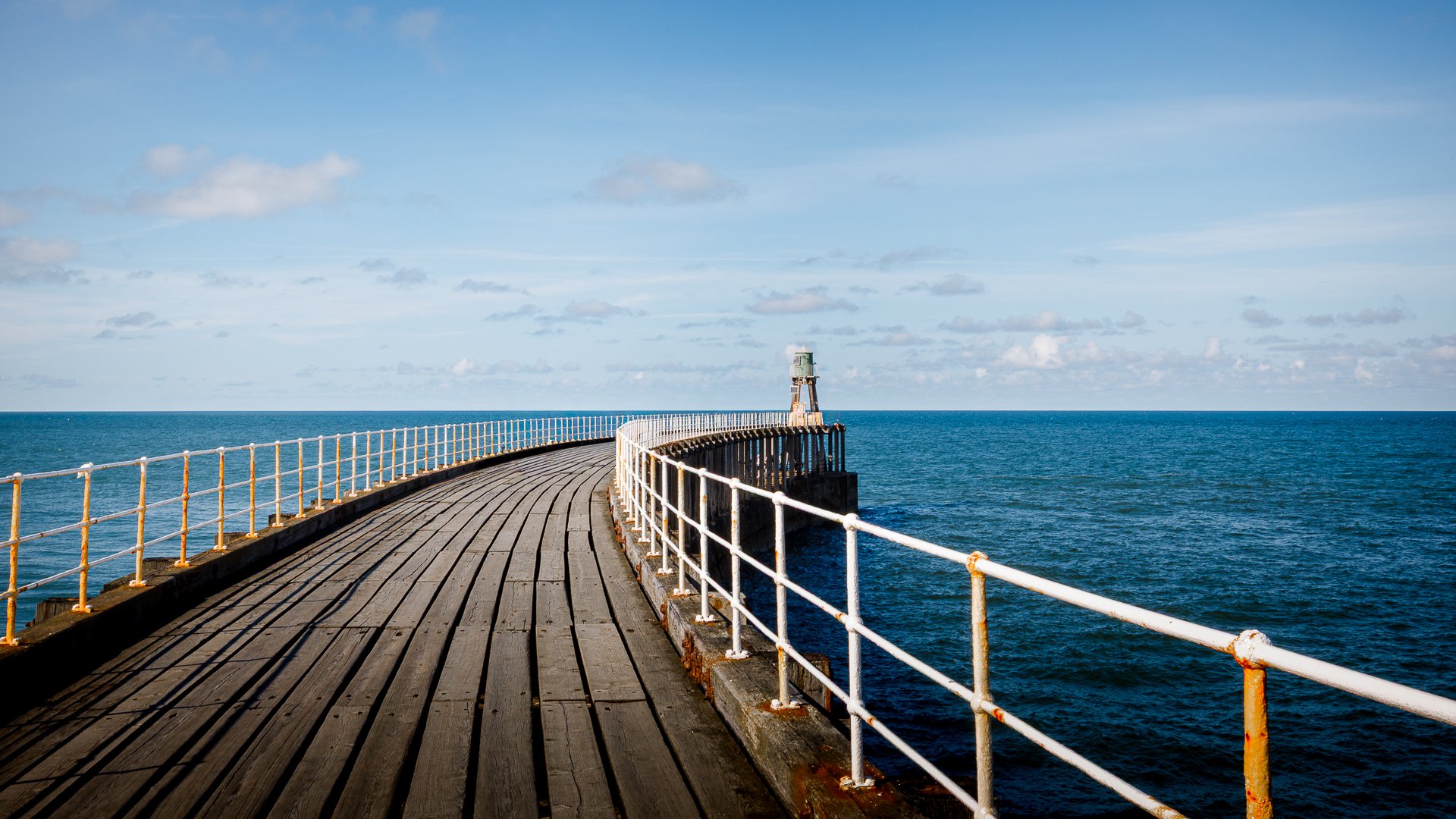 Whitby pier bending out to sea on a beautiful blue sky day usilising a long exposure and knowledge of the exposure triangle to expose the scene