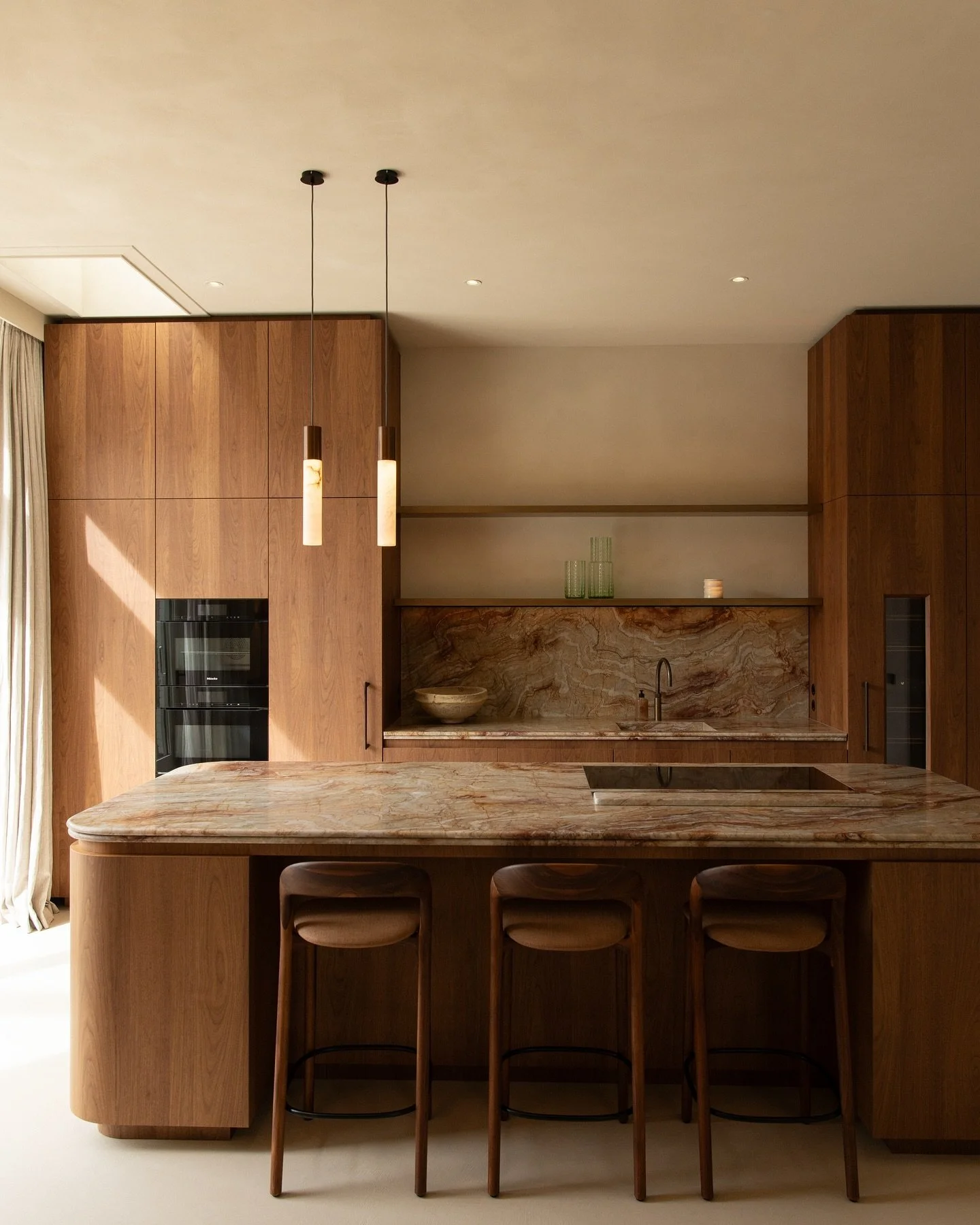 A stunning kitchen, which immediately draws attention upon entering the house. A standout feature is the exquisite Nacarado quartzite, which beautifully complements the warmth of the walnut wood used for the kitchen cabinets and island. Every small d