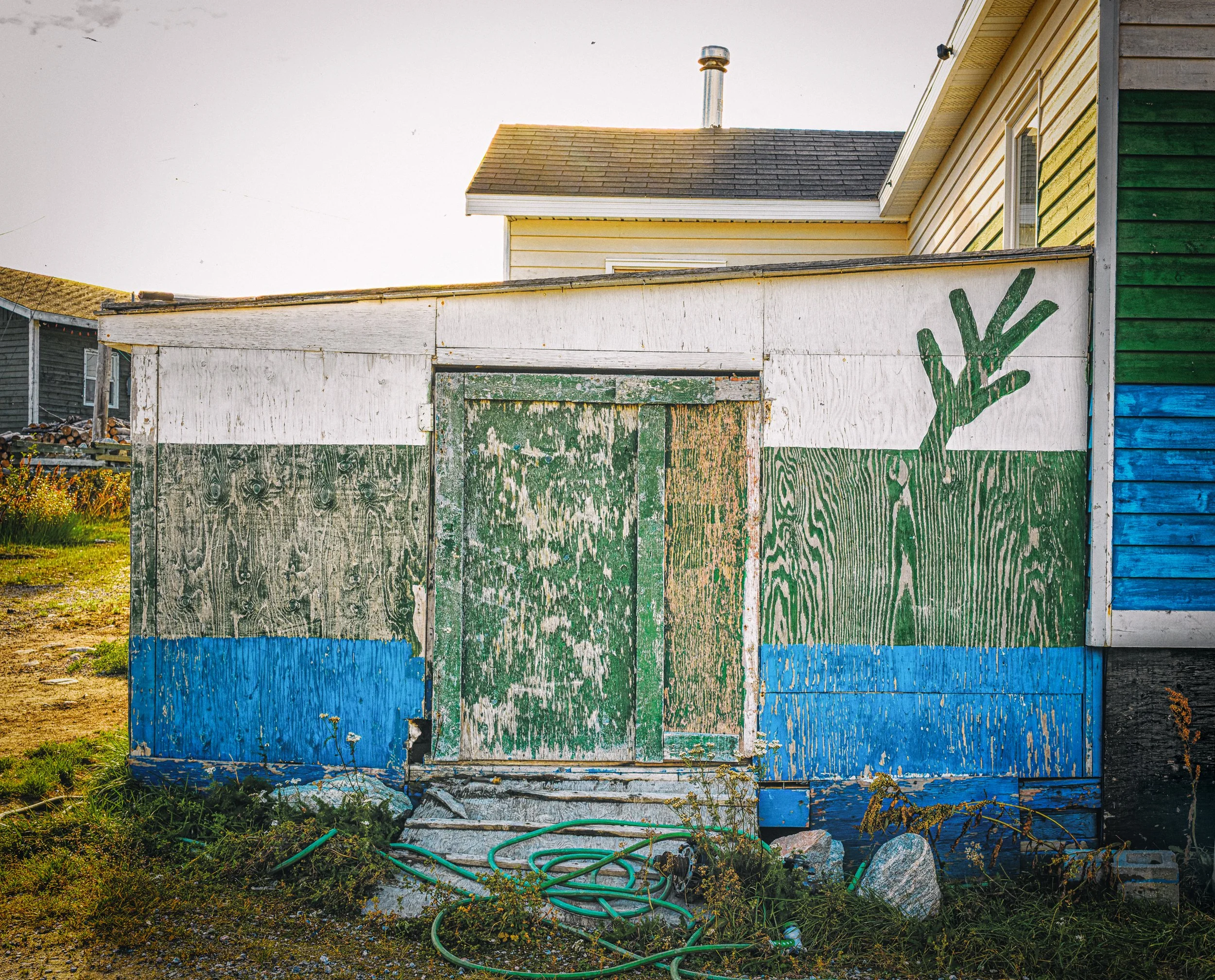 A shed painted with the unofficial Labrador flag in reverse.  The twig represents the Black Spruce, the official provincial tree.  Its three segments symbolize the unity of the Inuit, the Innu, and the European settlers. 