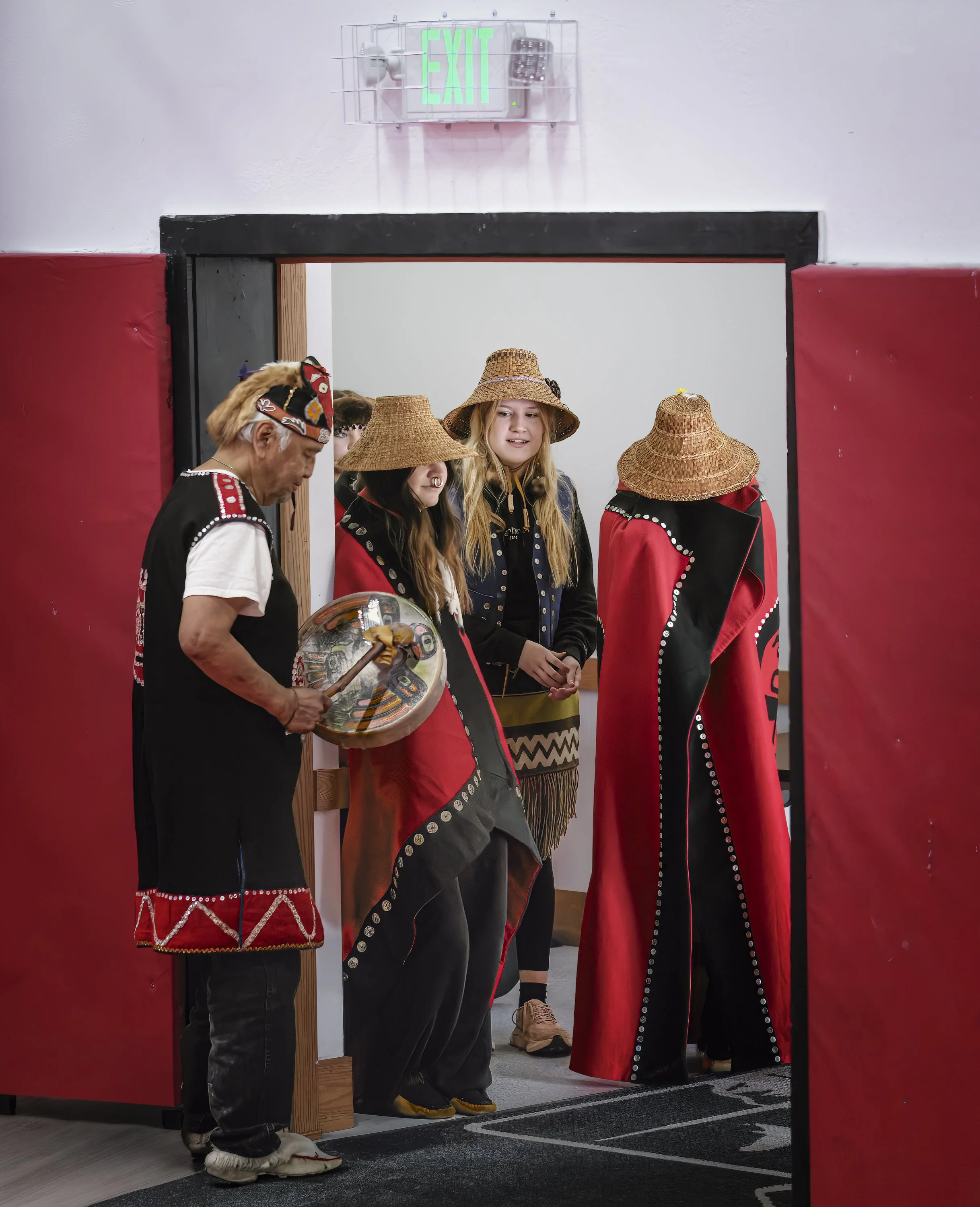 Getting ready to perform dances, wearing traditional garb passed down within families.  Kake.