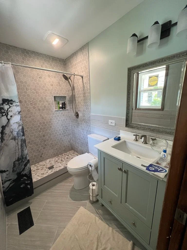 Completed primary bathroom renovation with standing shower, new toilet, new floor and wall tile, new vanity and new paint color