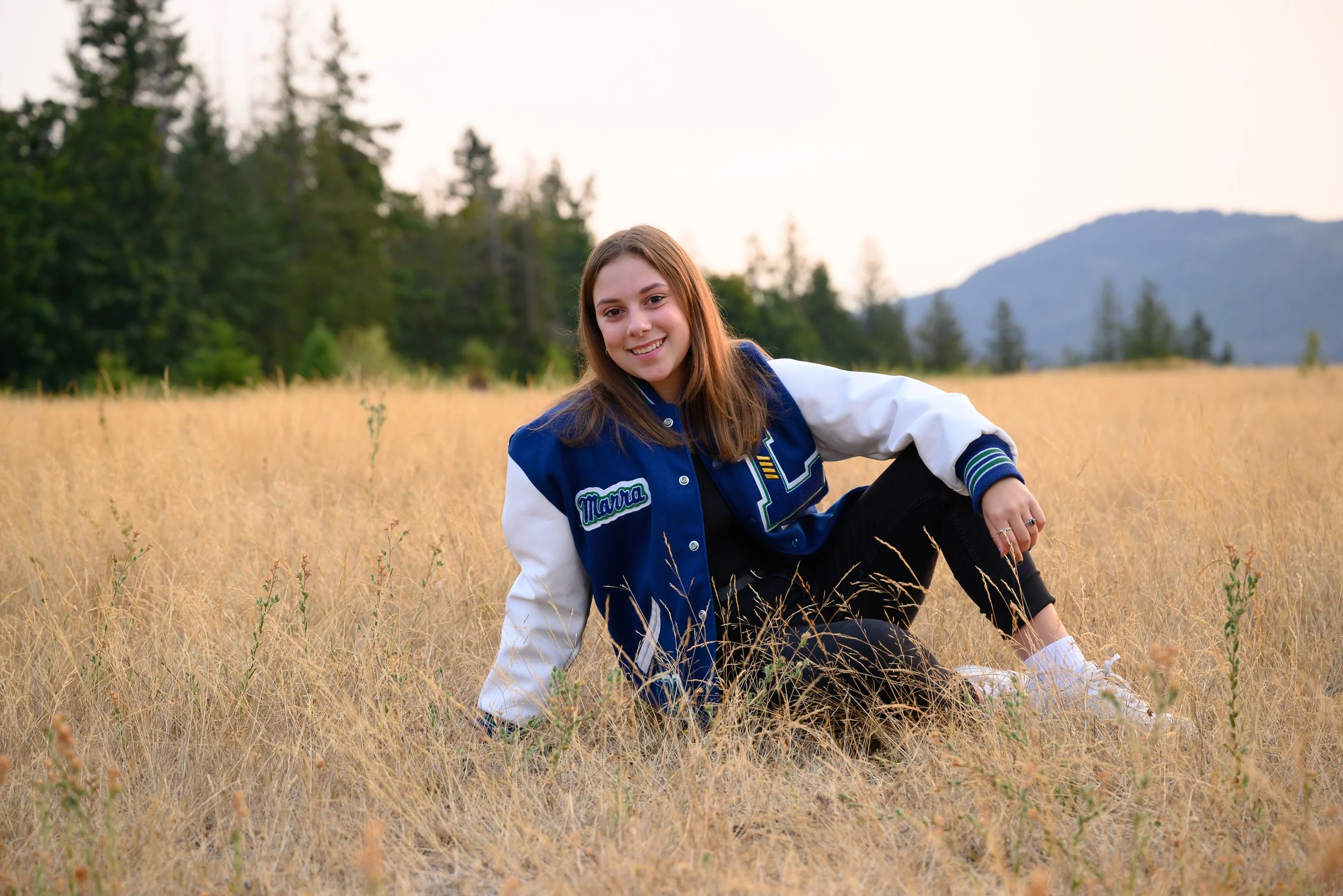 senior girl in field w letterman jacket