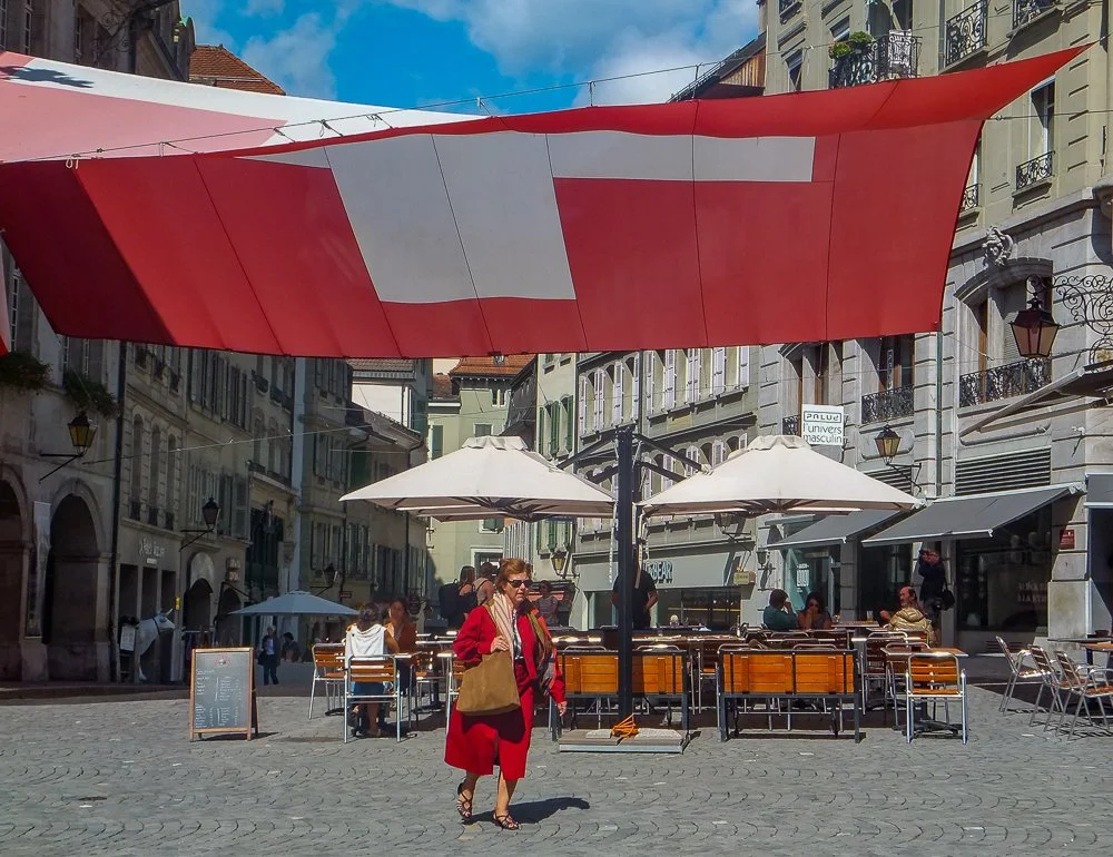 A woman in red walks beneath a massive Swiss flag on her way to work