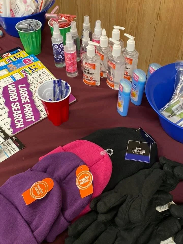 A table with hand sanitizer bottles, lip balm, books, gloves, and colorful socks.