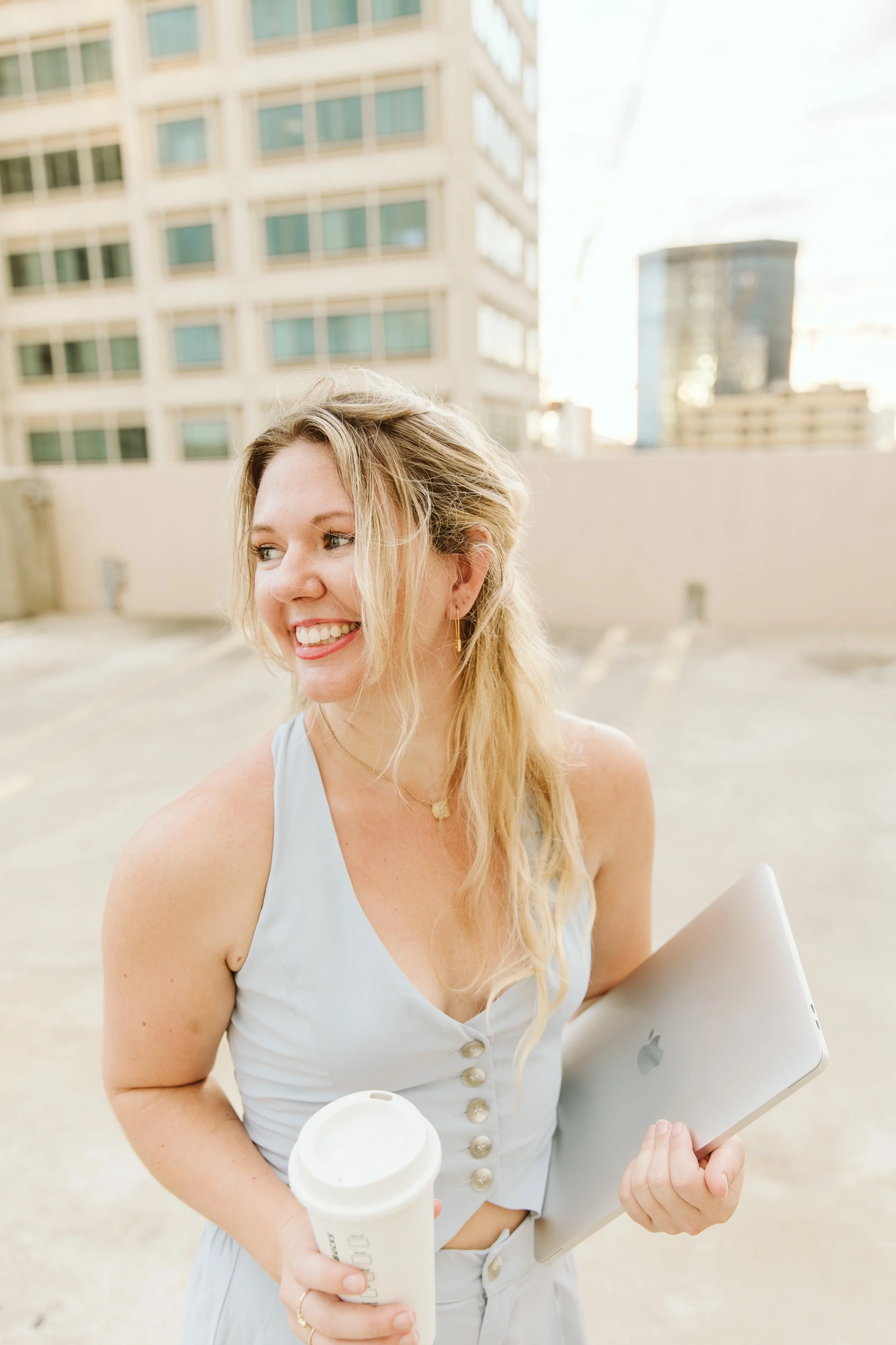 Tiffani holding a coffee cup and her laptop where she conducts her copywriting services