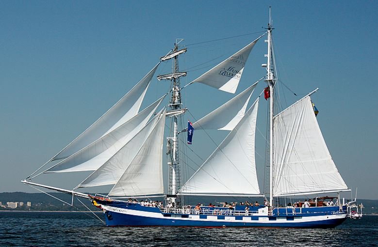 A large blue and white sailboat is floating in the ocean