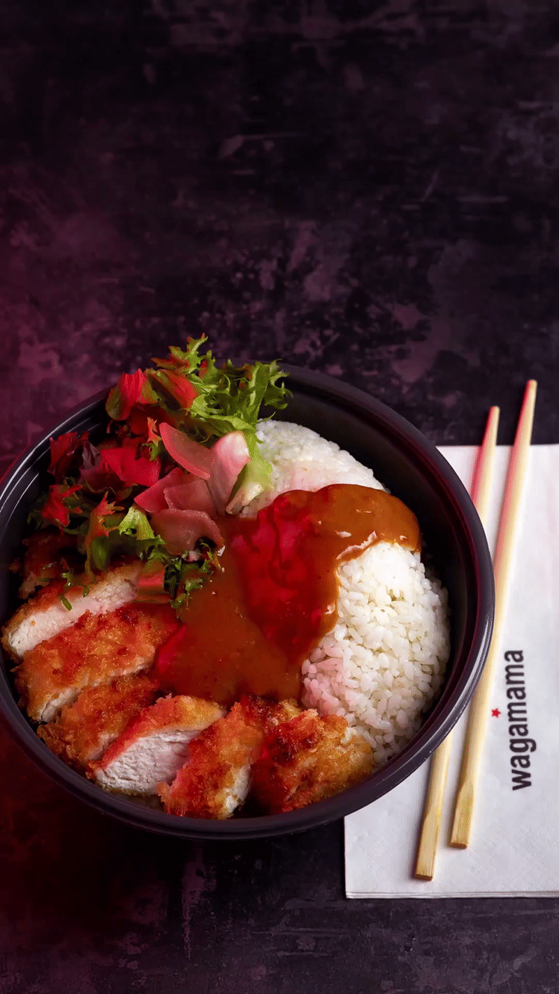 Bowl of fried chicken katsu curry with rice, lettuce, and pink pickled ginger next to chopsticks and a napkin.