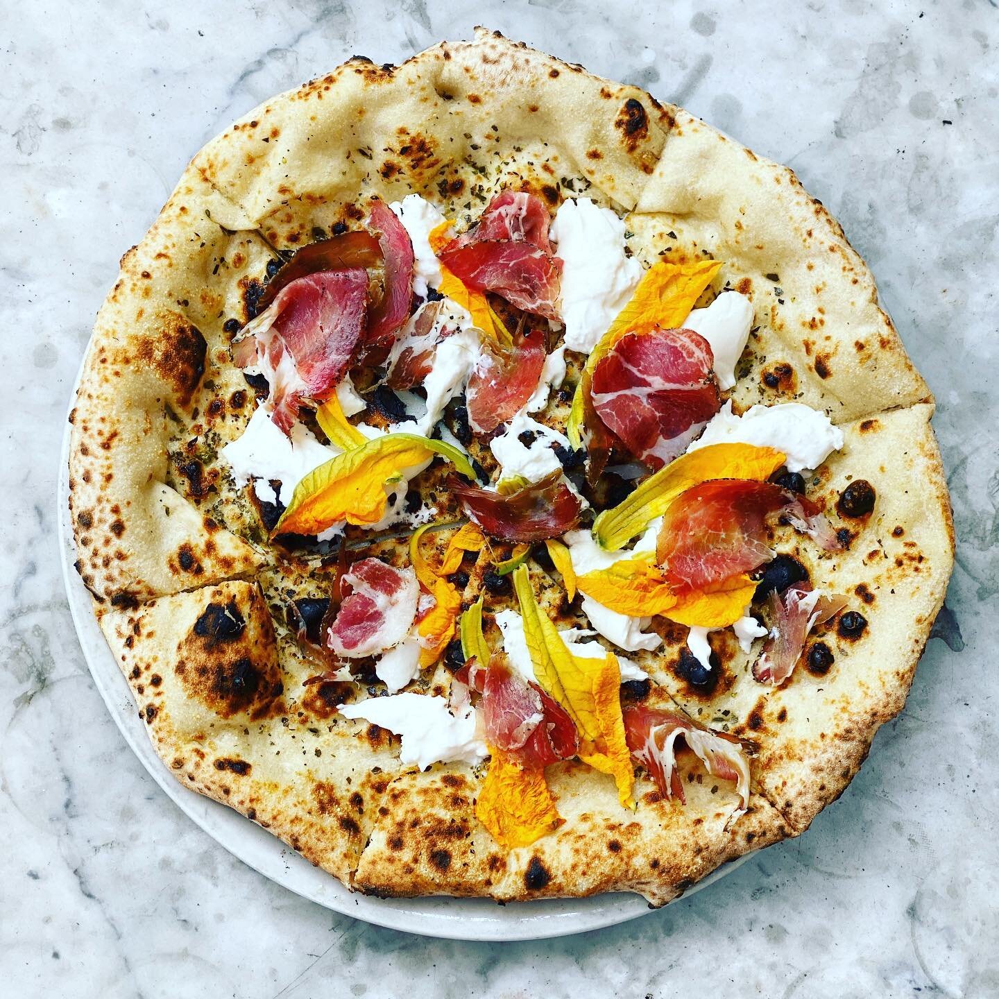 This Pizza Special is a seasonal delight with tangy Burrata, earthy Coppa, and slightly sweet zucchini blossoms all served on a perfect focaccia. 
#food #yummy #pizza #betterthannonnas