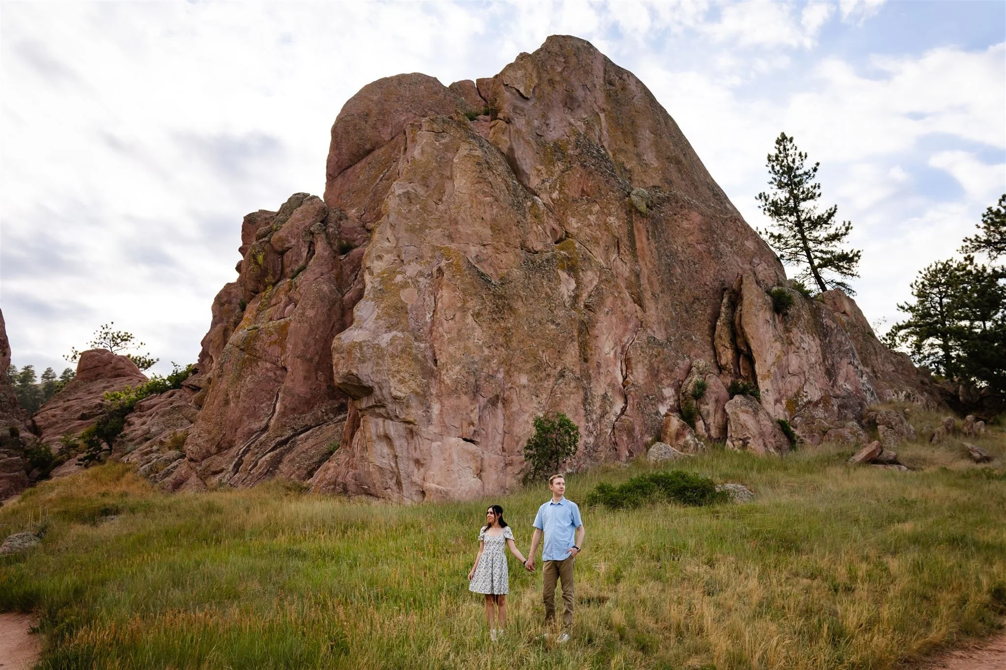 Couple standing in tall grass with large red rock formation