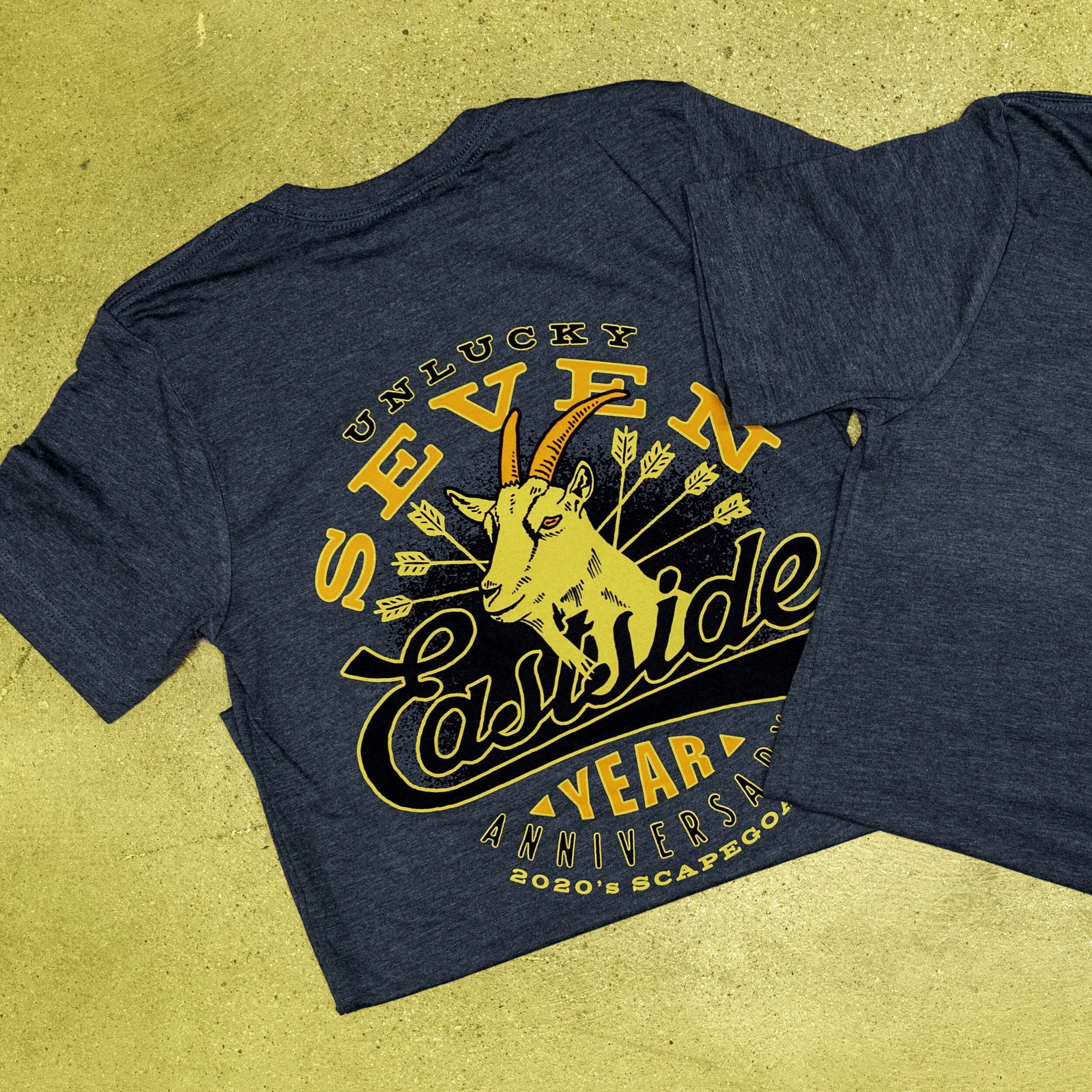 A navy blue t-shirt with a graphic design of a goat and the text 'Unlucky Seven' and 'Cashside' celebrating its 1-year anniversary in 2020.
