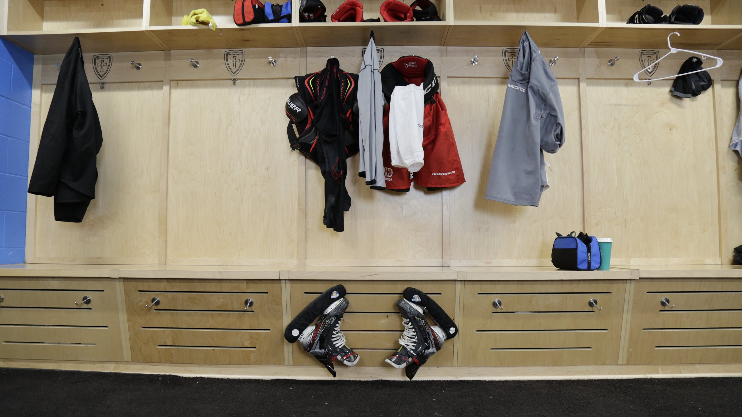  Each individual area in the customized sports center features a top shelf, two metal hooks for handing clothes or uniforms, and a lower bottom area complete with metal hooks for hanging skates.  