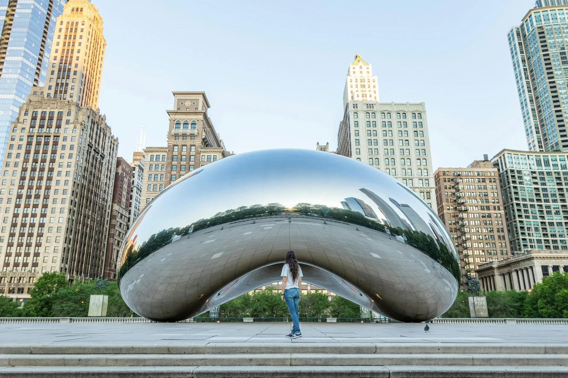 Cloud Gate or the Bean in Chicago mirrors a woman standing in front