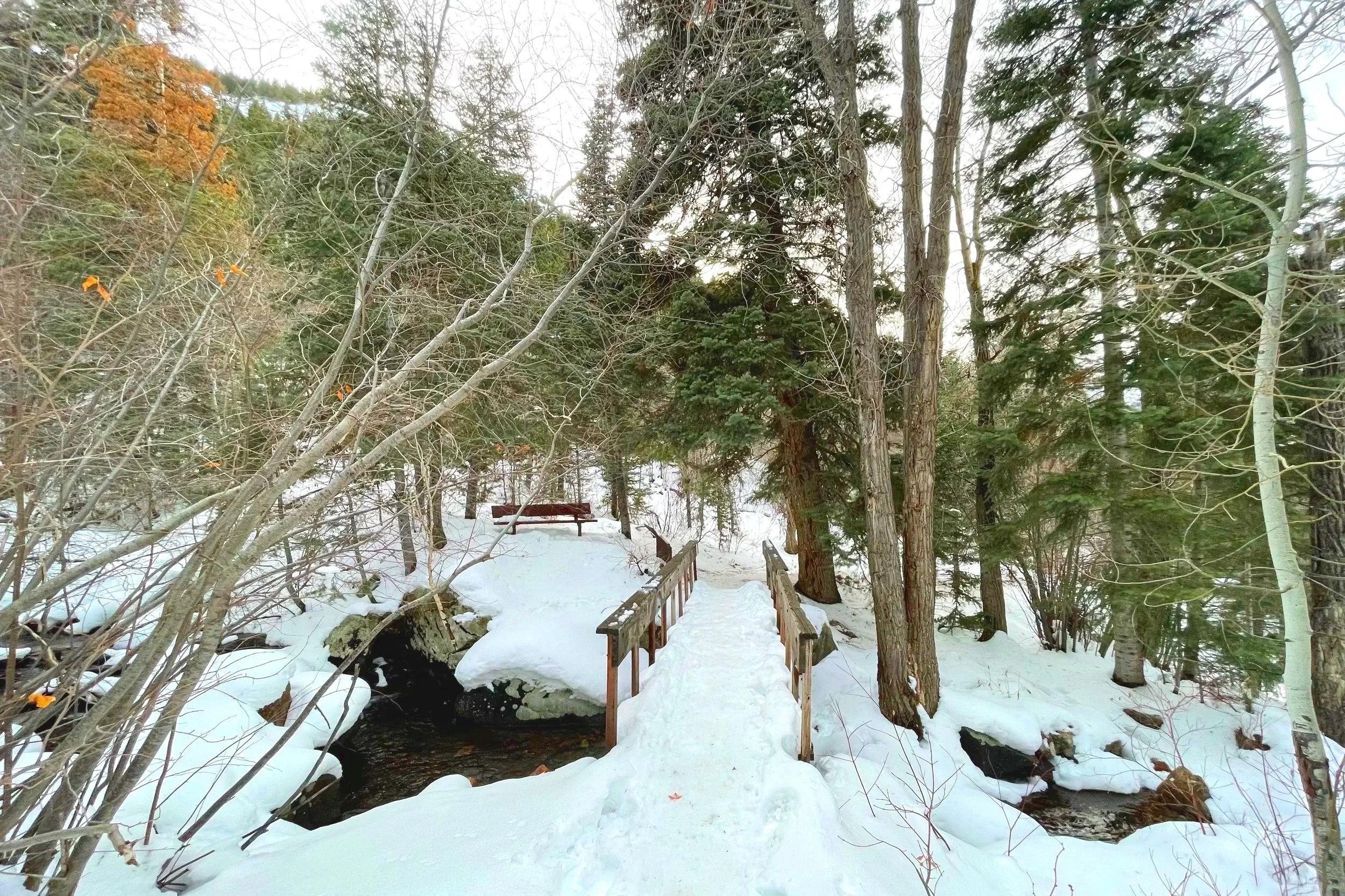 Hiking in the snow in spring on a trail with a bridge over a river