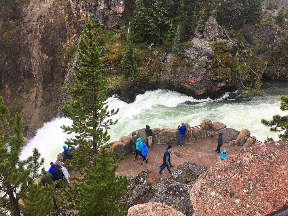 Grand Canyon of Yellowstone - View from above of roaring river and people dressed in blue and black rain gear