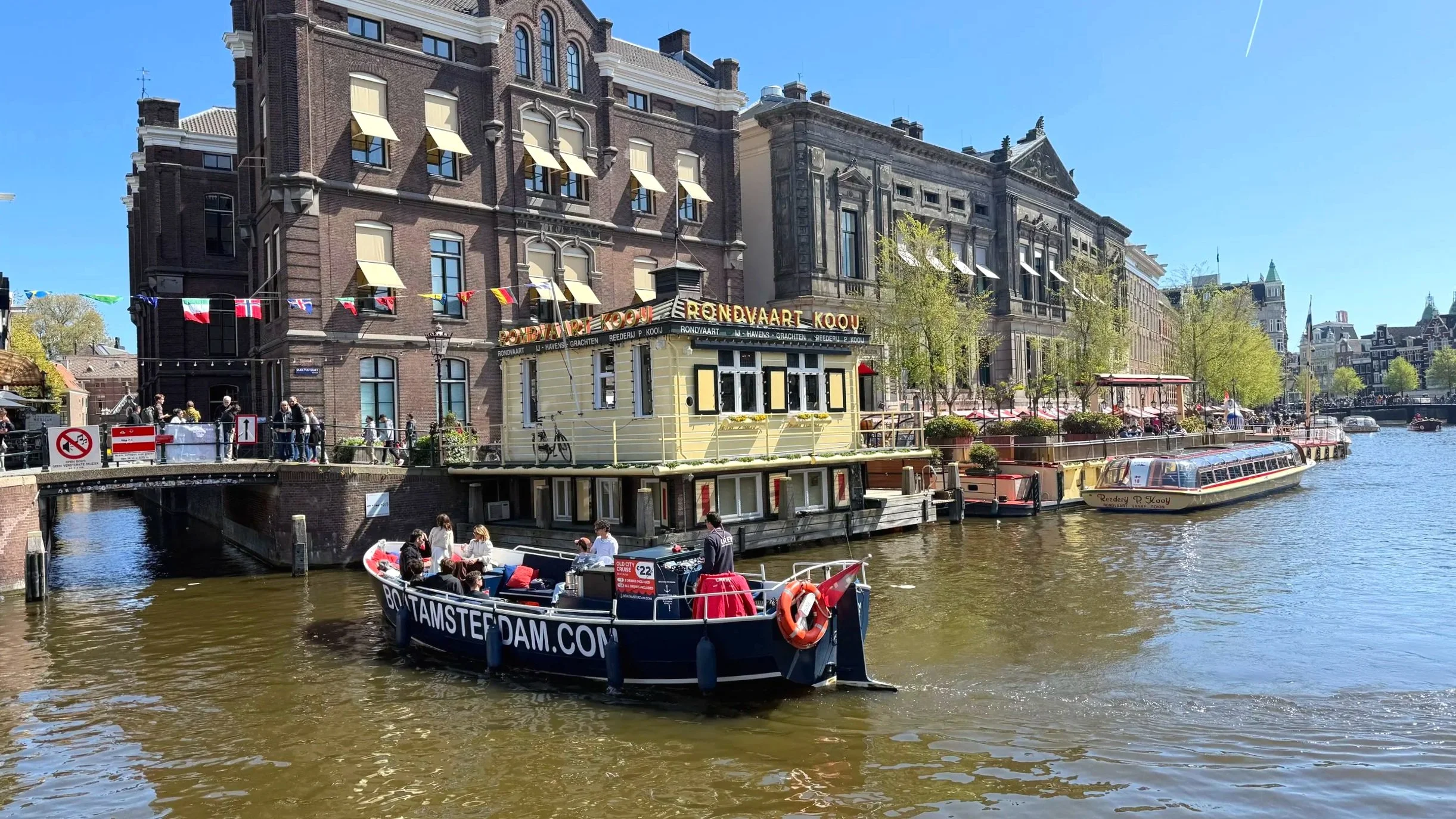 A large canal in Amsterdam holds many boats for canal tours