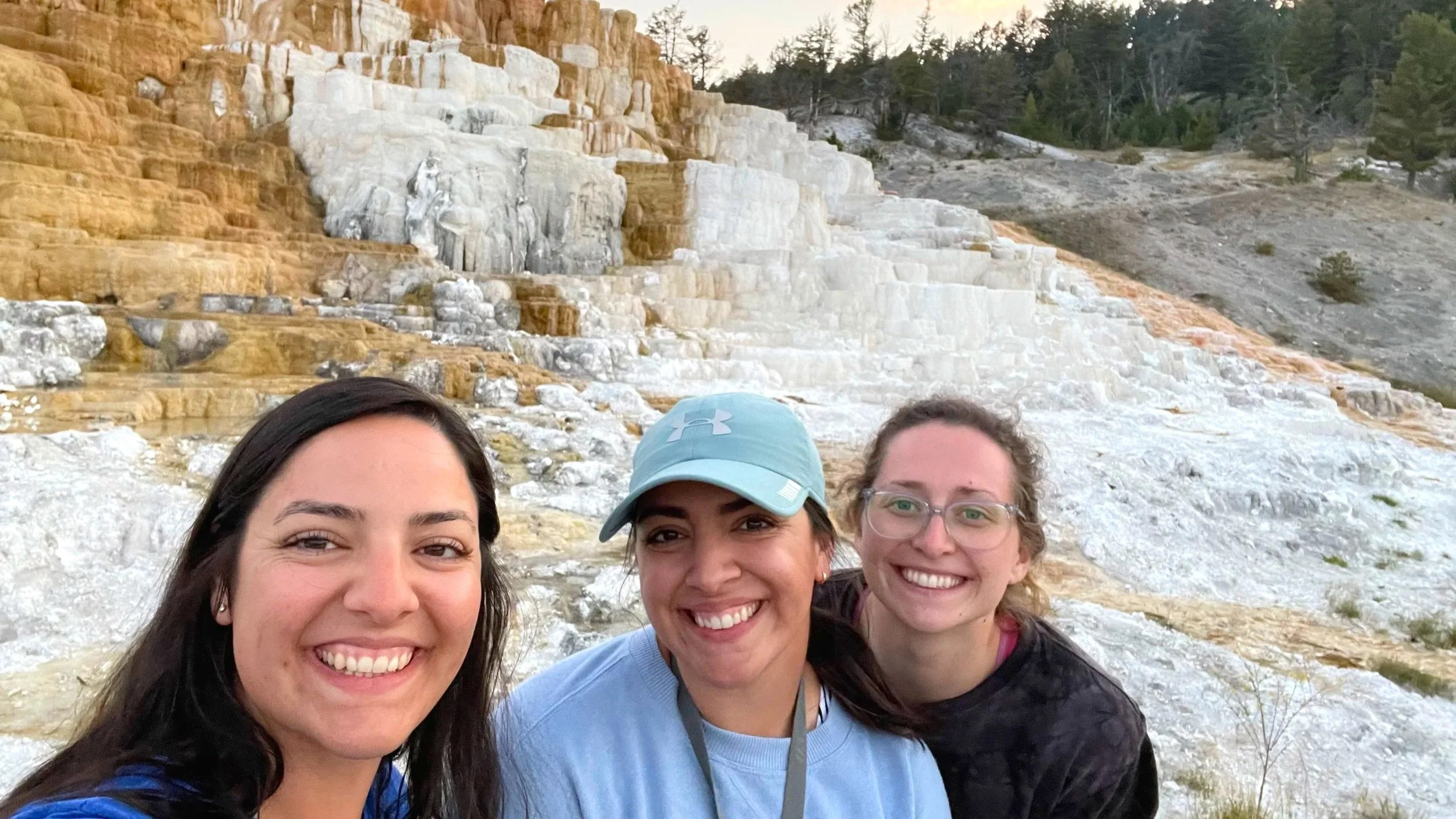 Three women pose in front of Mammoth Hot Springs in Yellowstone.