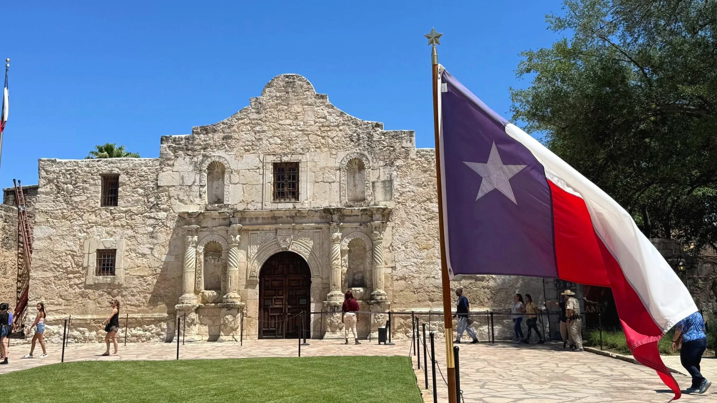 The Alamo next to a waving Texas flag is an iconic USA landmark.