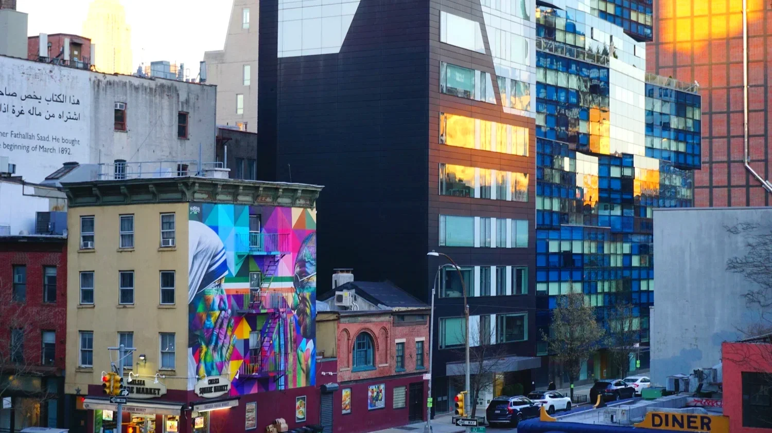 The sun bounces off the windows of New York buildings near a mural of Mother Theresa and Ghandi