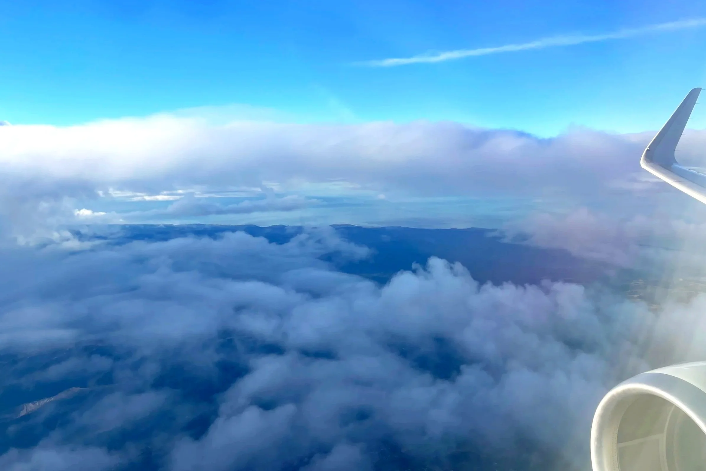 Clouds in the sky with a wing of the plane showing.