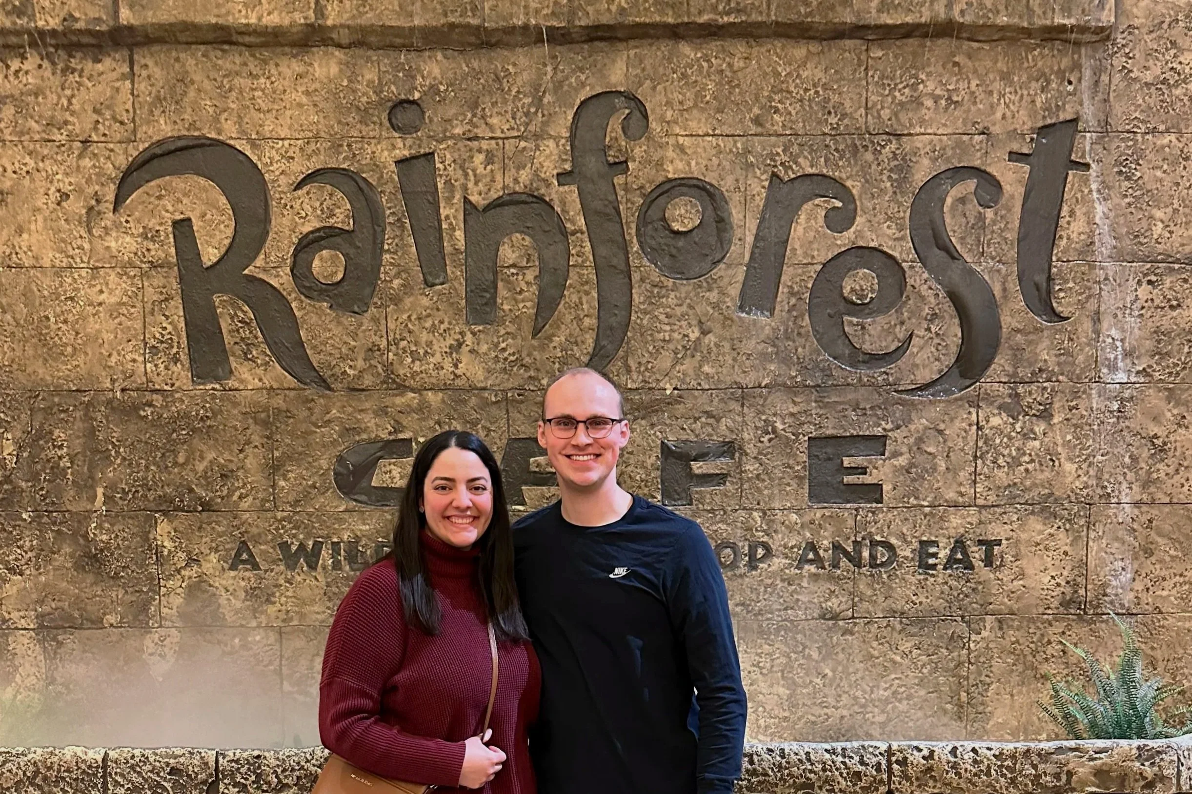 A couple poses in front of the Rainforest Cafe sign in Grapevine Mills.