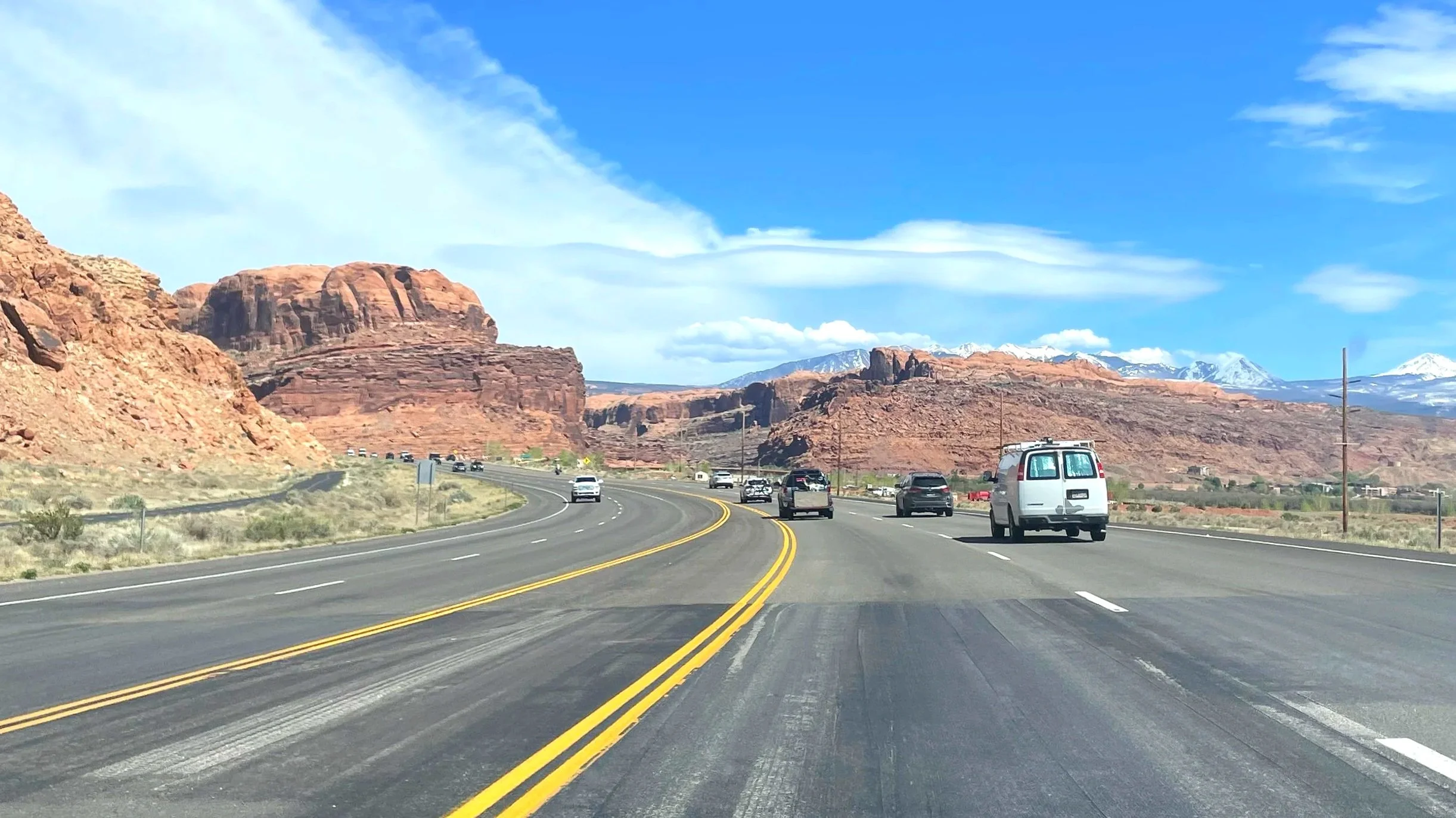 Road trip through southern Utah with red rocks all around and snowy mountains in the distance.