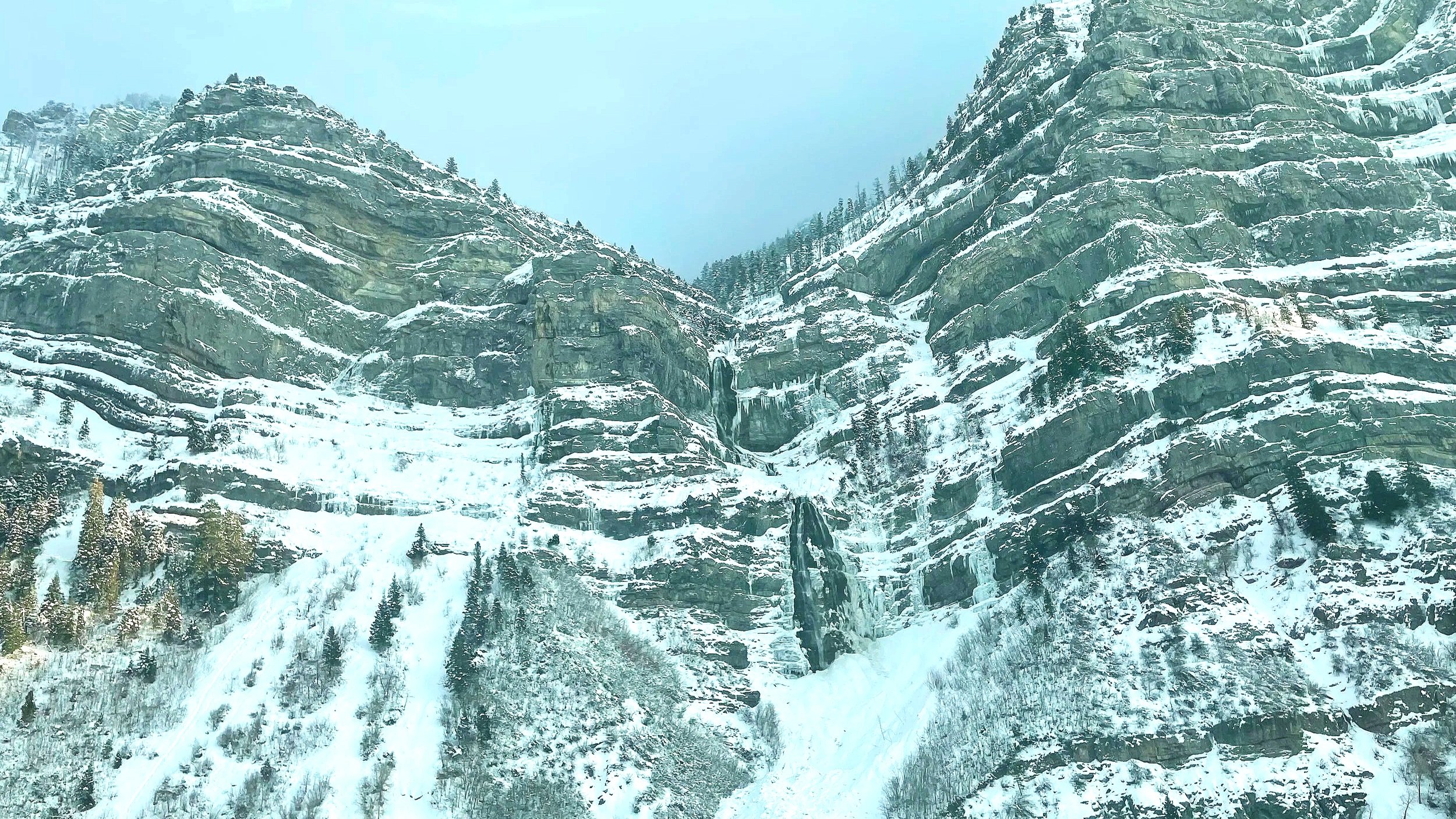 A frozen Bridal Veil Falls is surrounding by snowy mountains in Provo Canyon, Utah.