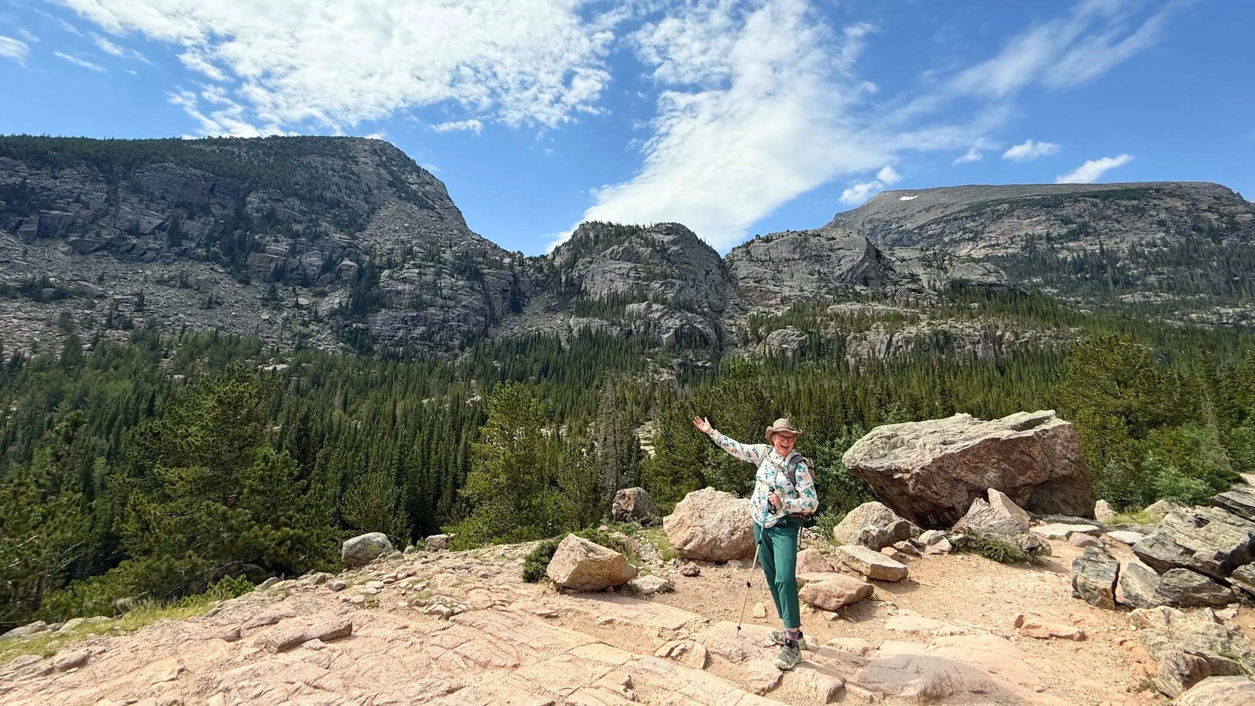 A solo woman hiker points out the beautiful scenery in Rocky Mountain National Park.