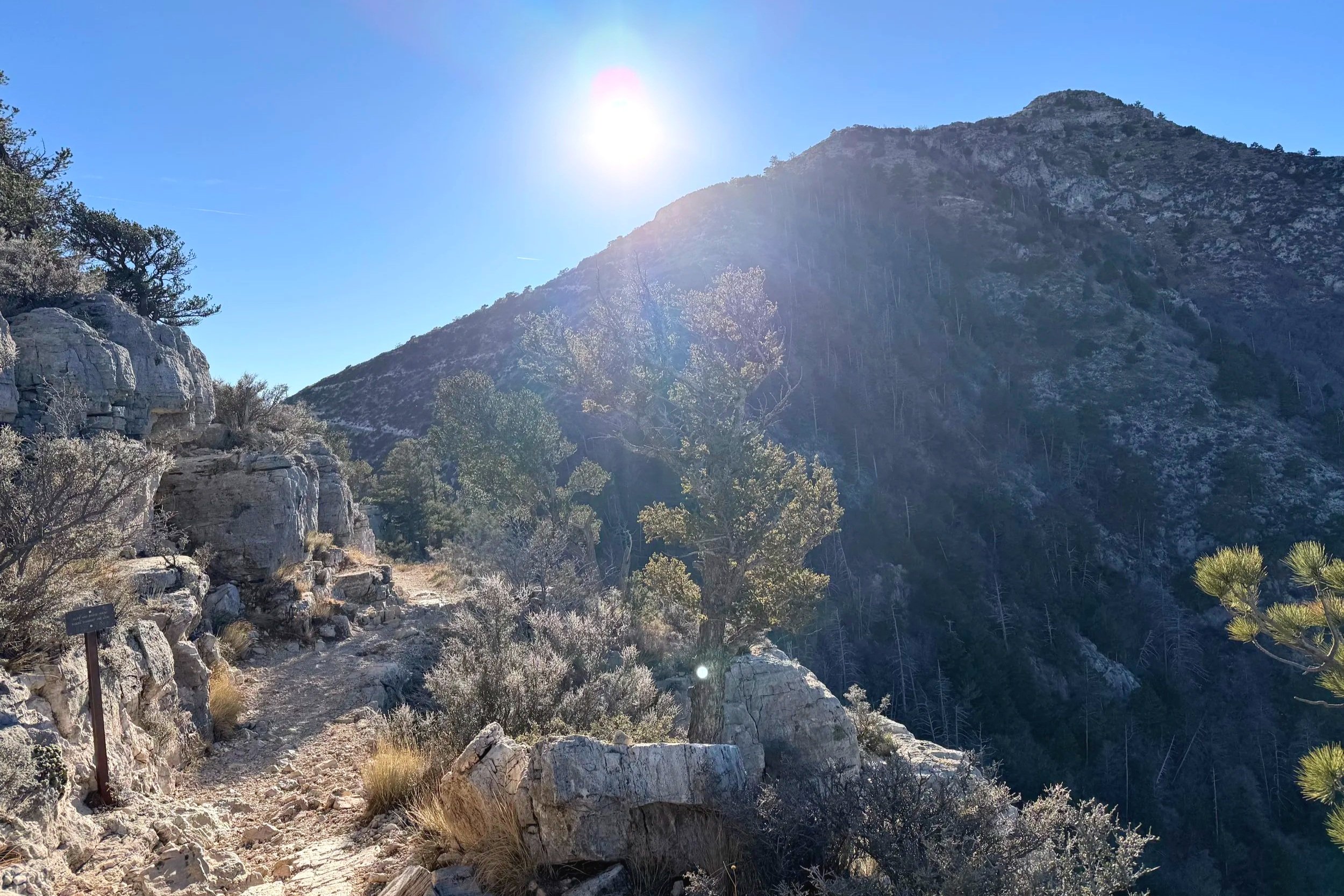 The sun shines fiercely on a desert mountain trail.