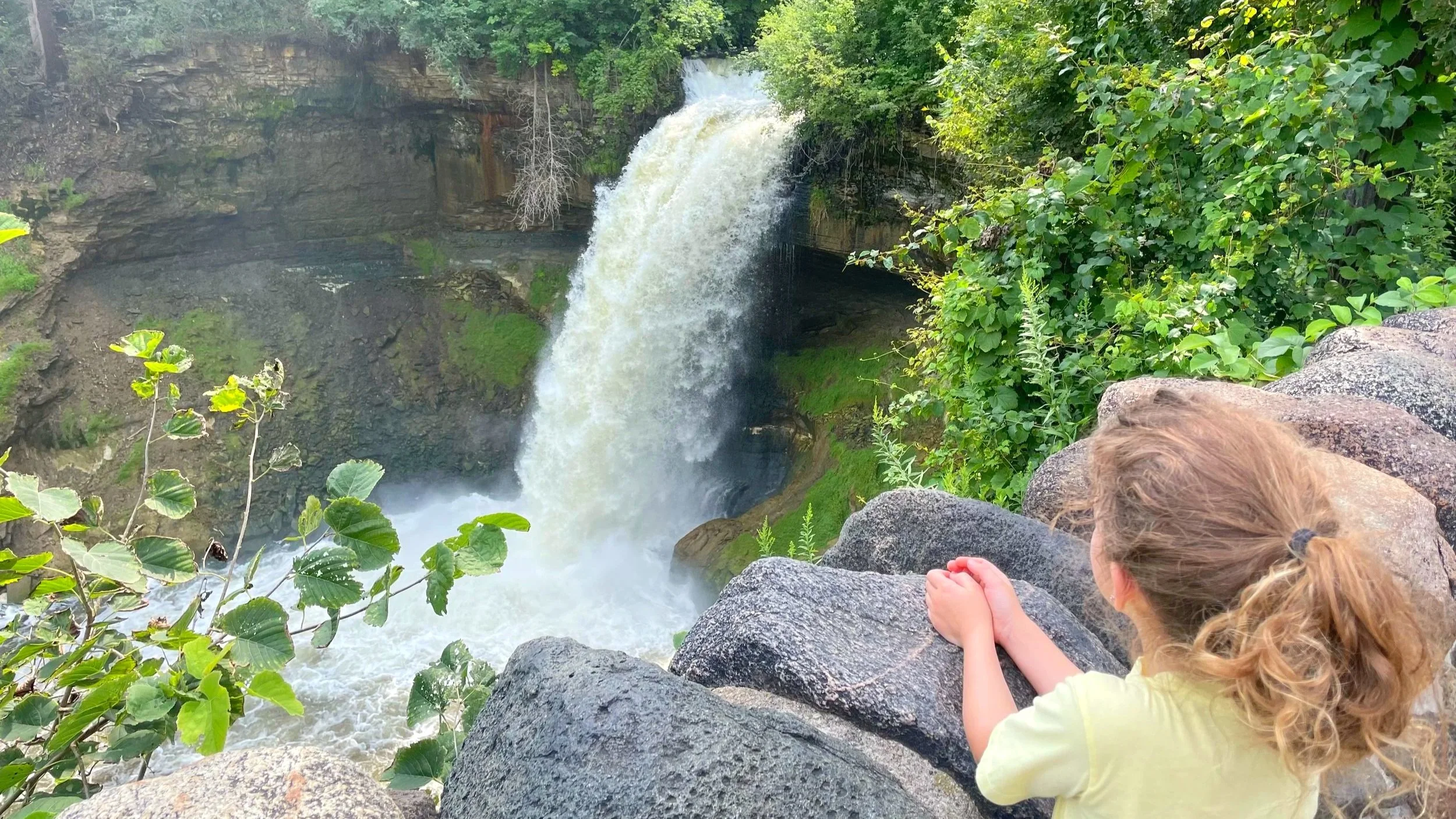 A young girl watches a waterfall on a hike