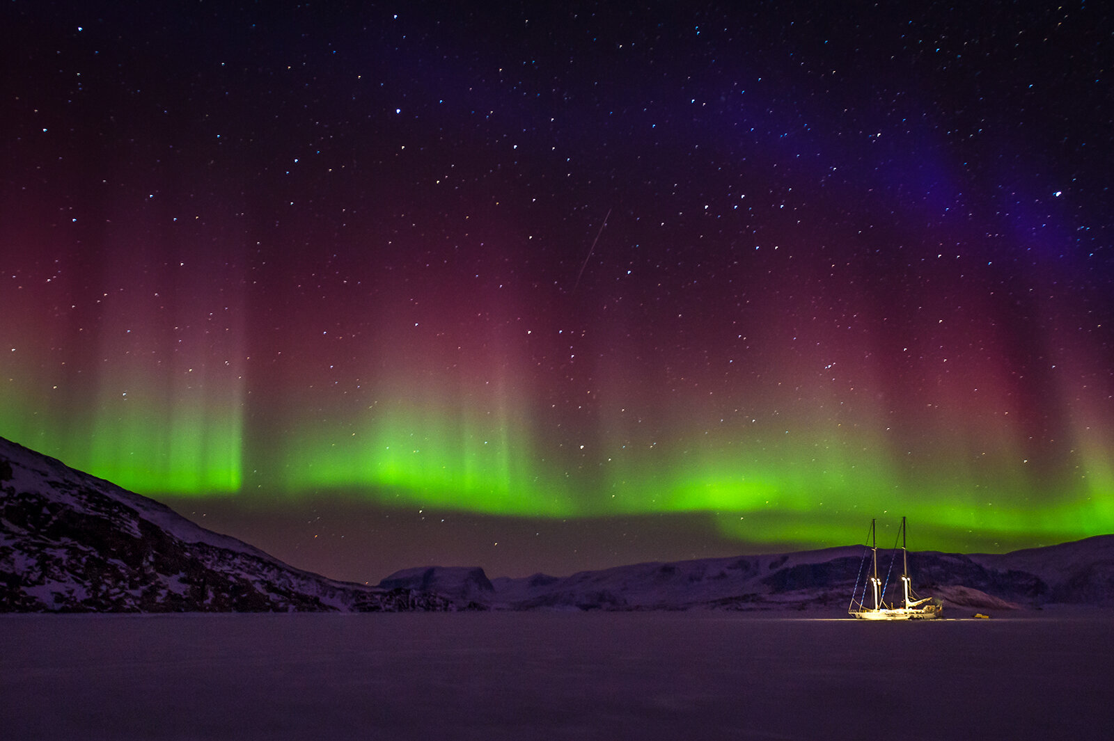 Boat caught in the sea ice under the northern lights