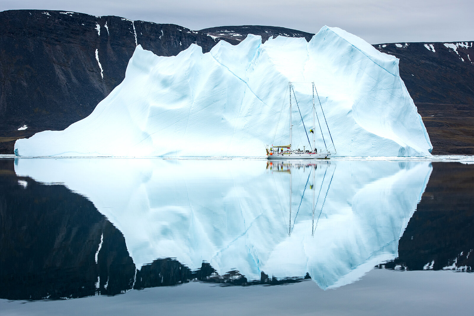 Expedition boat passing by a giant iceberg