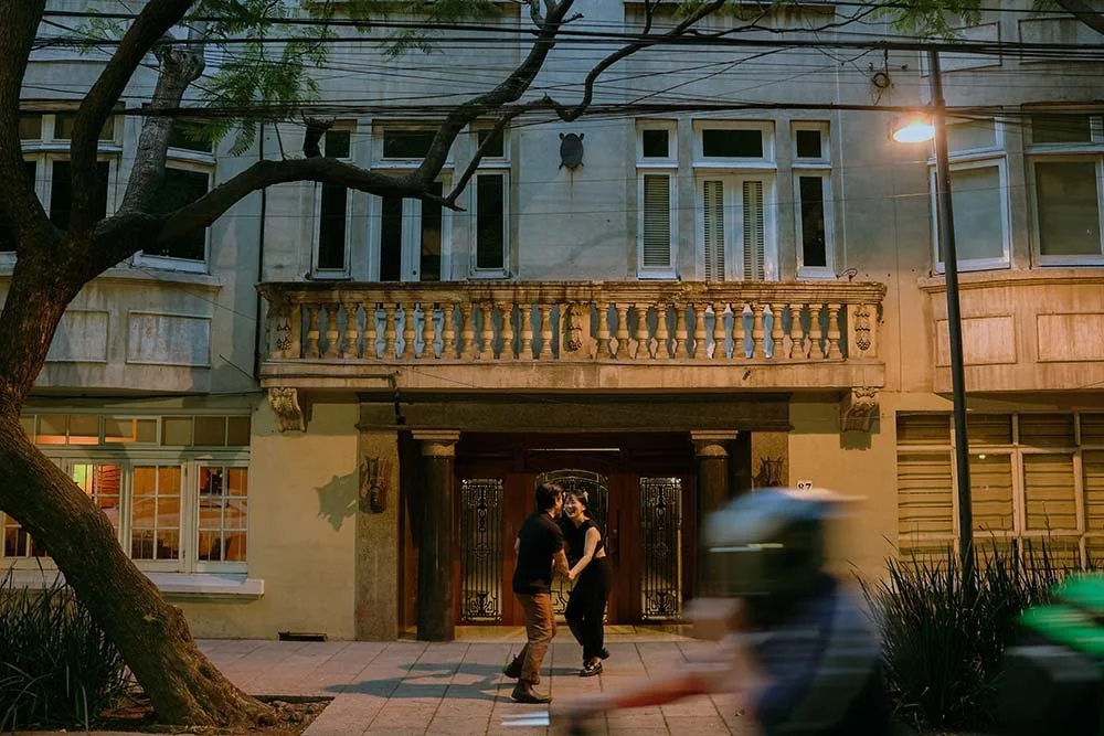 Couple walking along a Condesa street at night, captured with cinematic city lights and motion blur in Mexico City.
