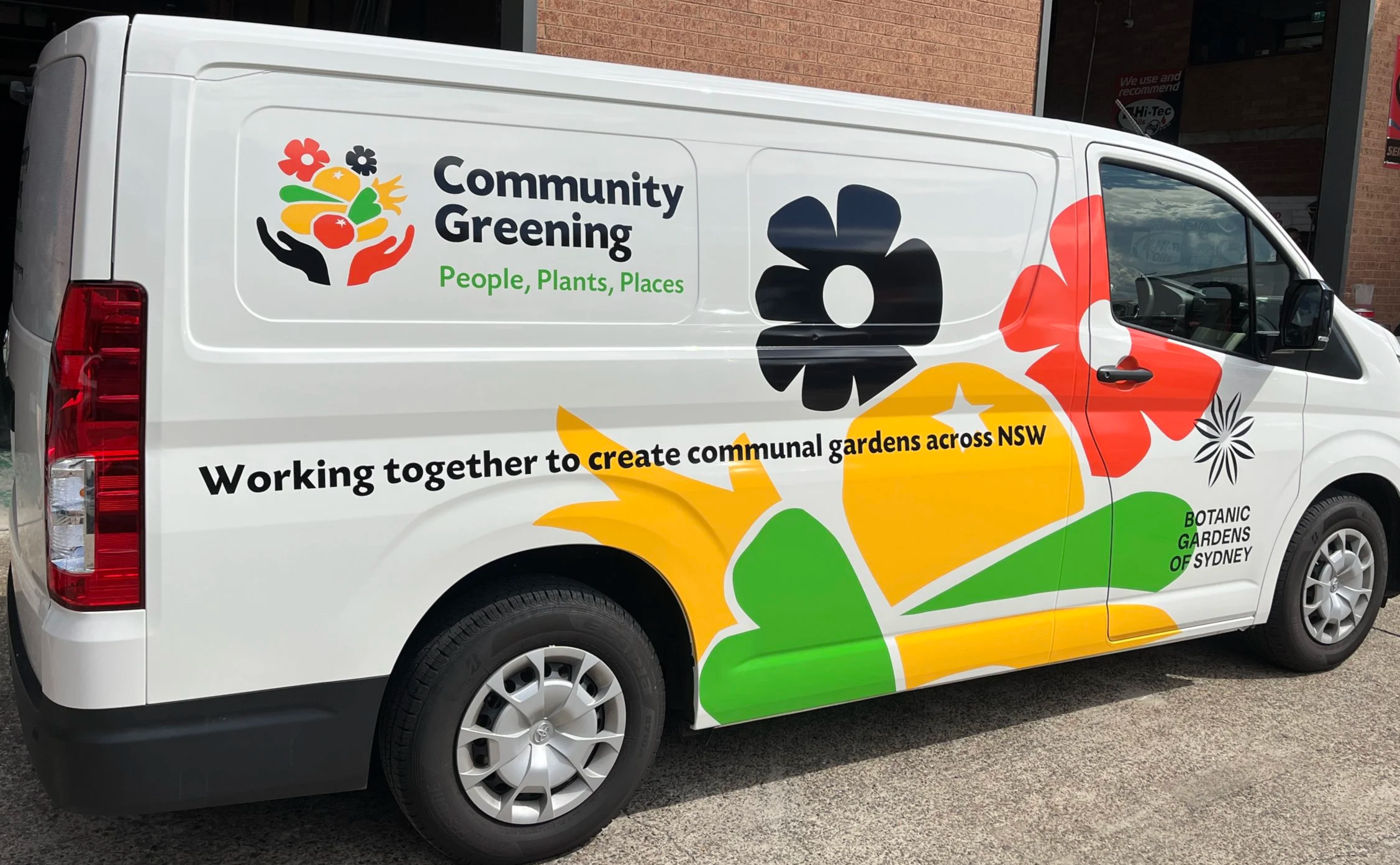 White Community Greening van with colourful flower graphics and organisation branding.