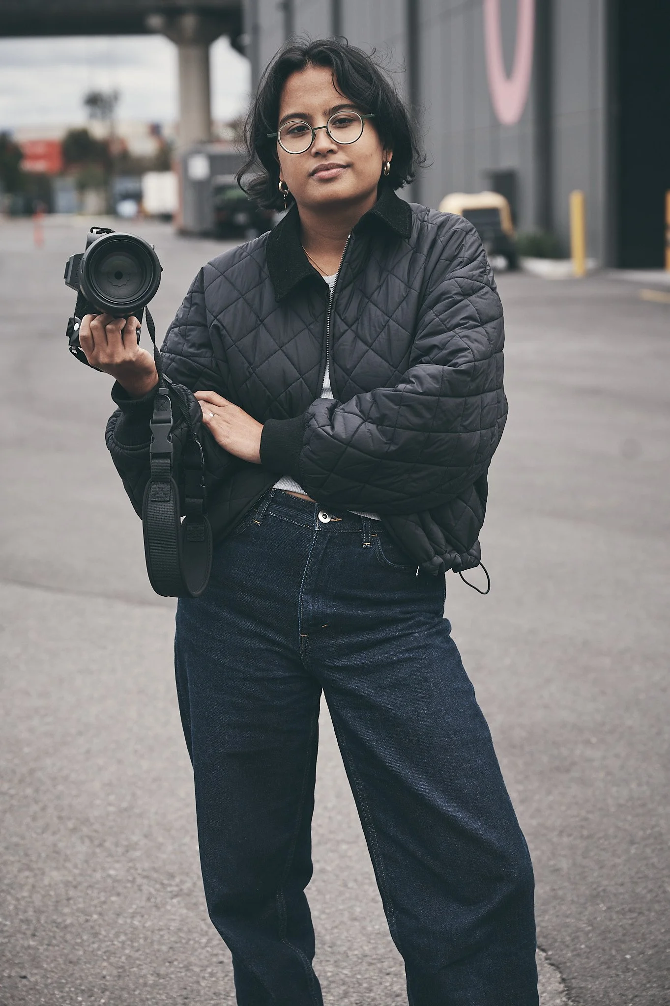 a photographer stands confidently, holding a camera in their hand