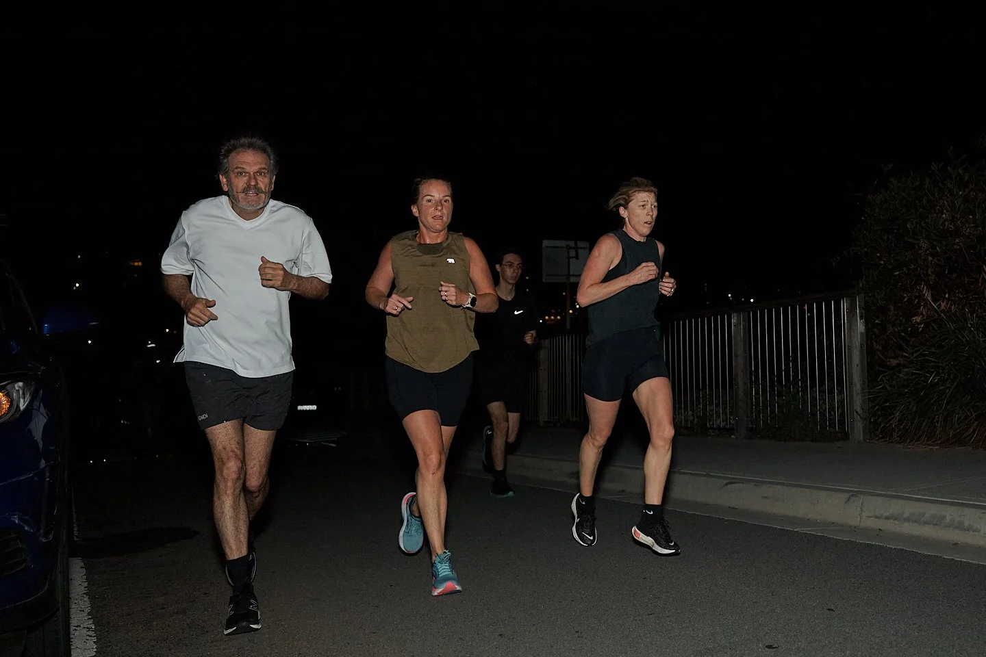 Four people running outdoors at night.