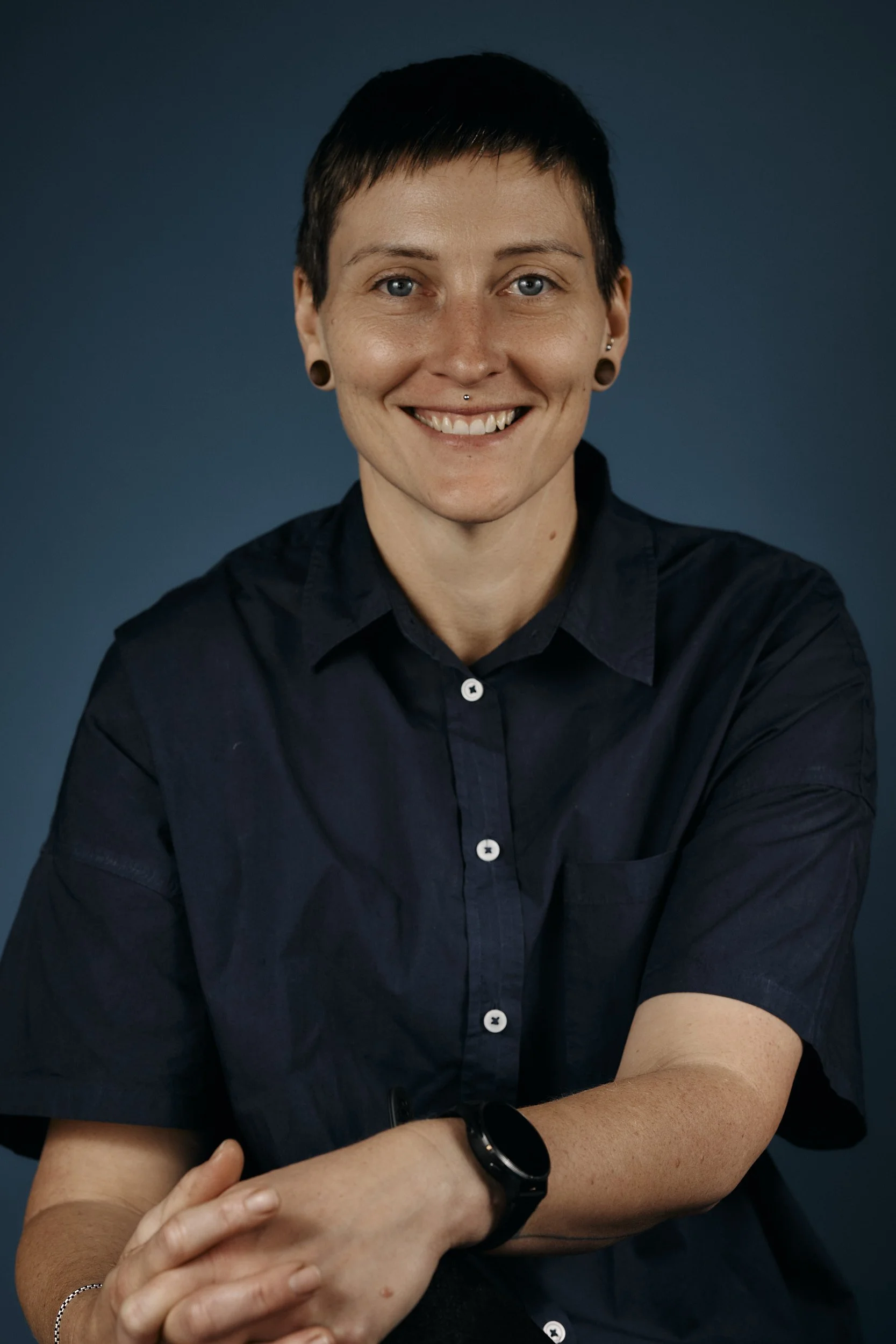 a portrait of a person sitting in front of a blue backdrop
