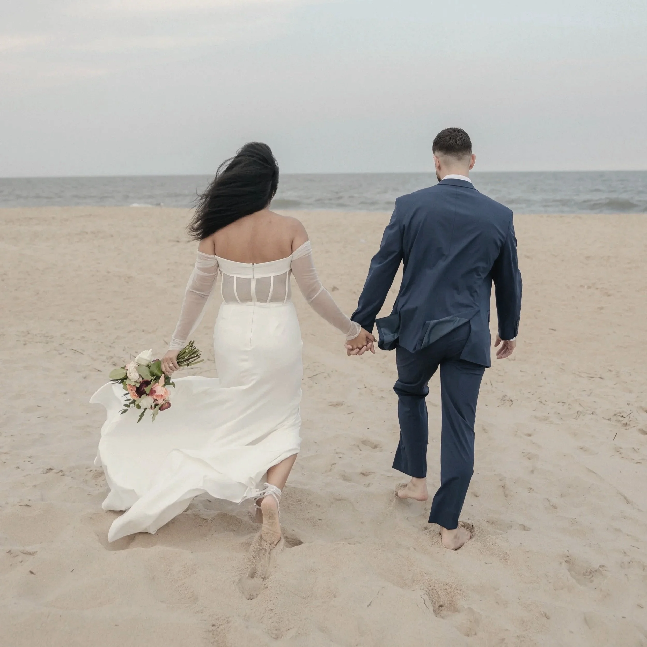 Romantic beach elopement or vow renewal in Ocean City, MD, with Barefoot Bride Weddings, featuring a couple exchanging vows under a beautifully decorated arch by the ocean.