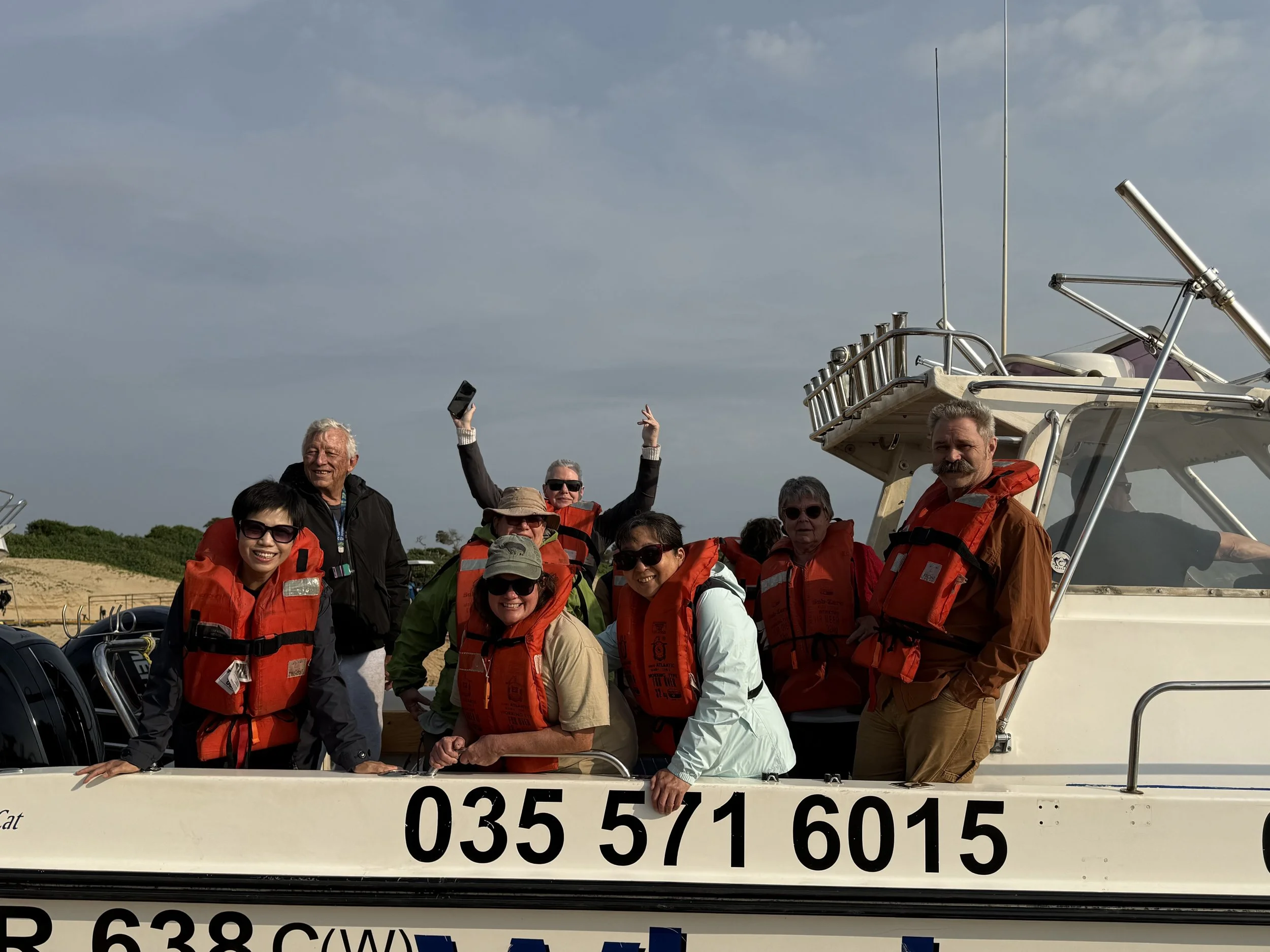 IMG_7239_tour members on boat hands up.jpeg