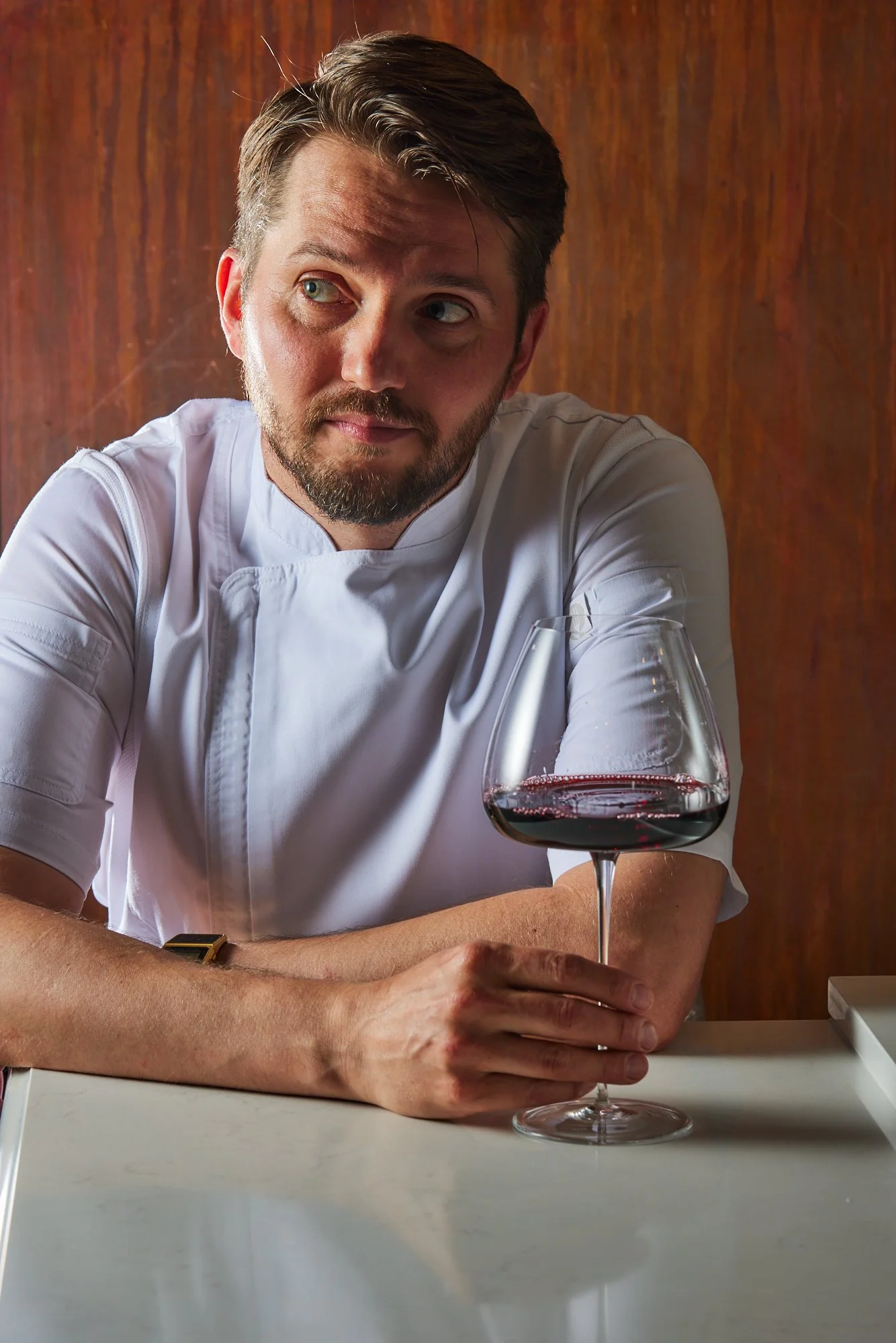 Multi Michelin-Origin Chef Miles in his chef whites with a glass of red wine