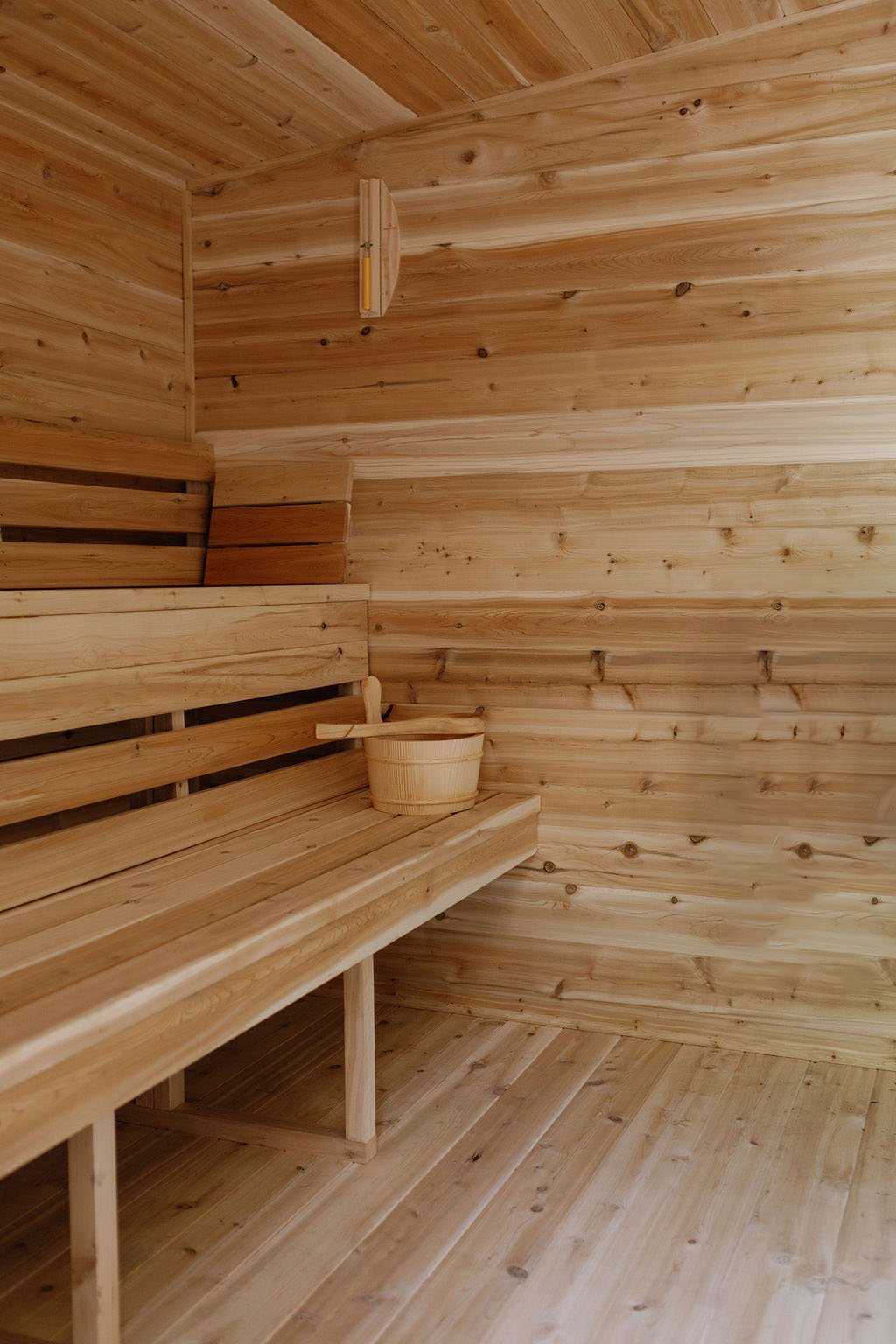 Interior of private cedar sauna room with benches and a sauna bucket located in The Ayrshire Laigh's spa.
