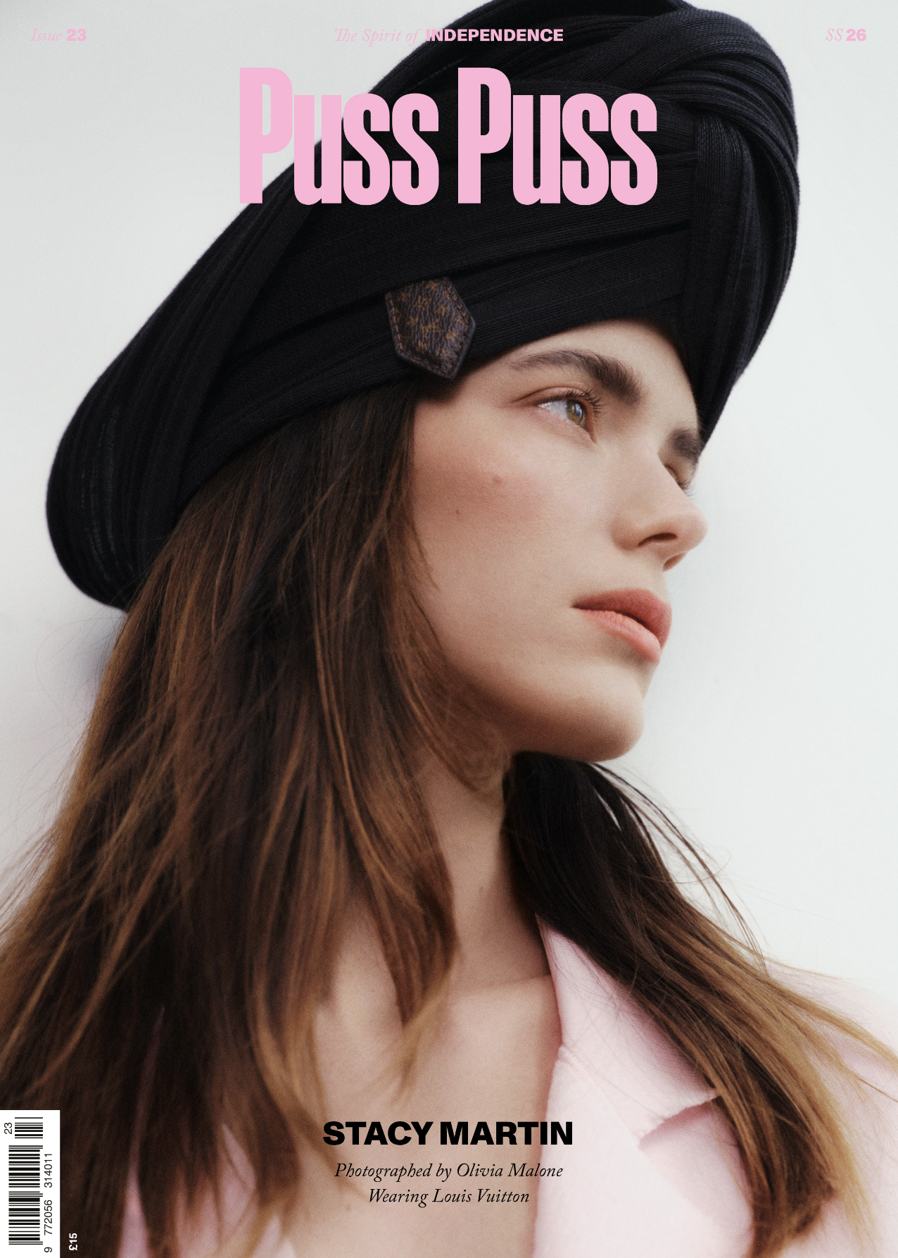 Close-up of a young woman with long brown hair wearing a black Louis Vuitton hat and a light pink shirt, looking to the right against a plain white background.
