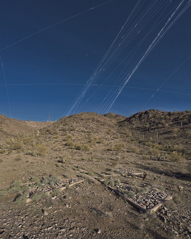  A web-like pattern streaks through the desert sky with concrete slabs in the foreground. 
