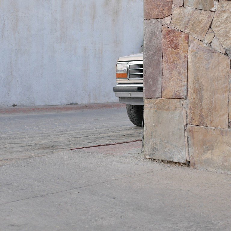  The front of a truck peeks out behind a stone wall. 