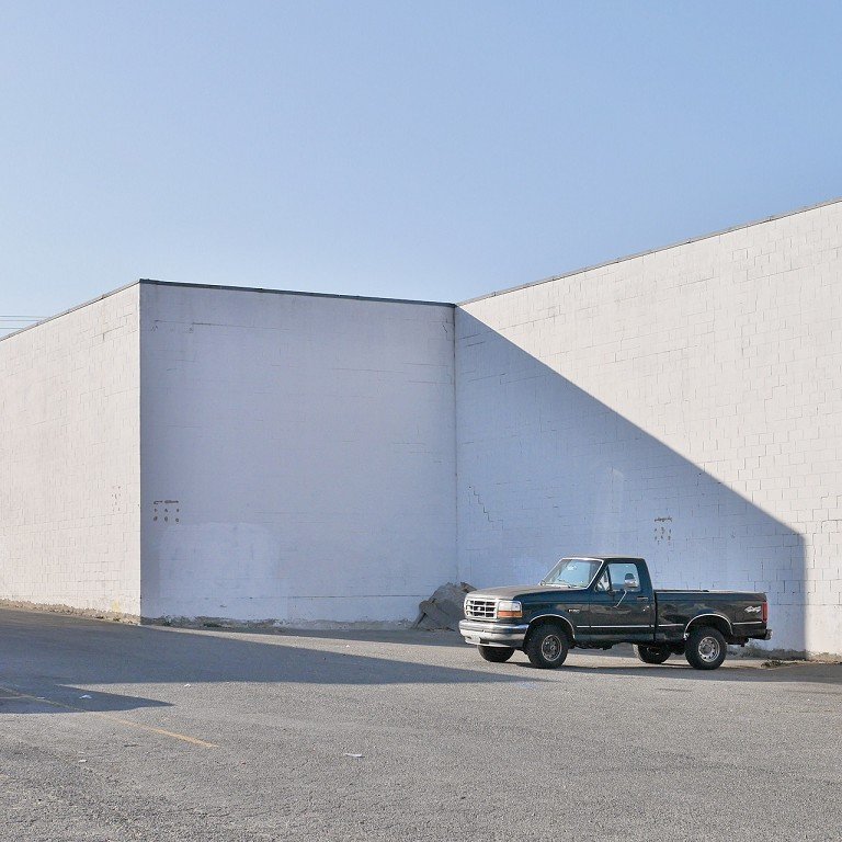  A truck parked next to a white building. 
